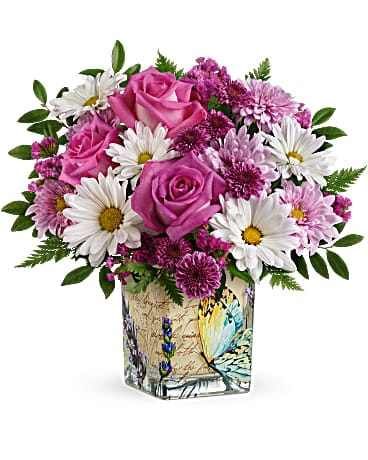 Teleflora's Vintage Butterfly Bouquet - Make their spirit soar with this vintage-inspired vase, adorned with whimsical butterflies and bursting with the prettiest pink roses and daisies! Hot pink roses, purple button spray chrysanthemums, lavender cushion spray chrysanthemums, white daisy spray chrysanthemums and raspberry sinuata statice are arranged with leatherleaf fern and huckleberry. Delivered in a Vintage Butterfly Cube.