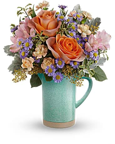 Teleflora's Aqua Amour Bouquet - Ring in the spring with gorgeous garden blooms in an aqua-glazed stoneware pitcher--it's food safe for years of beverage pouring pleasure! This arrangement includes peach roses, pink alstroemeria, miniature peach carnations, large purple monte cassino asters, dusty miller, seeded eucalyptus and pitta negra. Delivered in a Garden Beauty Pitcher.