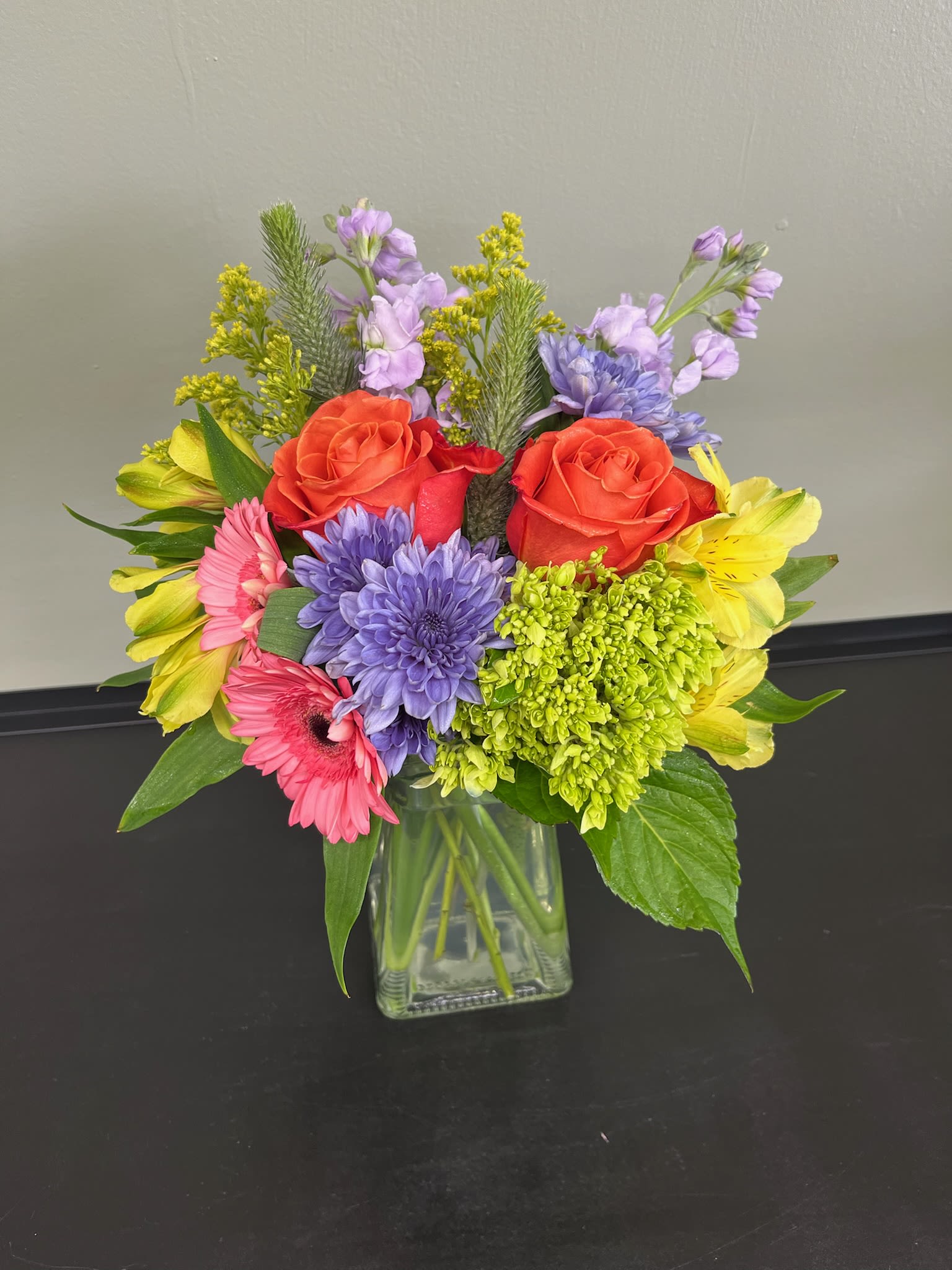Mixed bouquet in a clear glass vase with roses, daisies, and alstroemeria