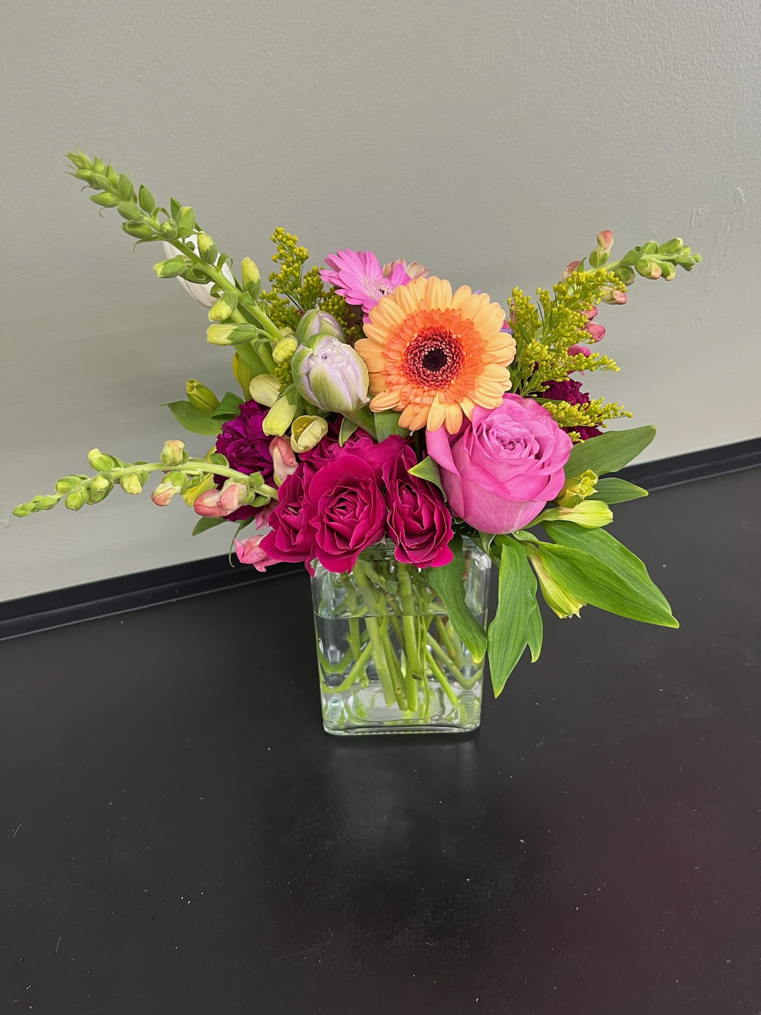 Mixed bouquet in a clear glass vase with pink and orange blooms