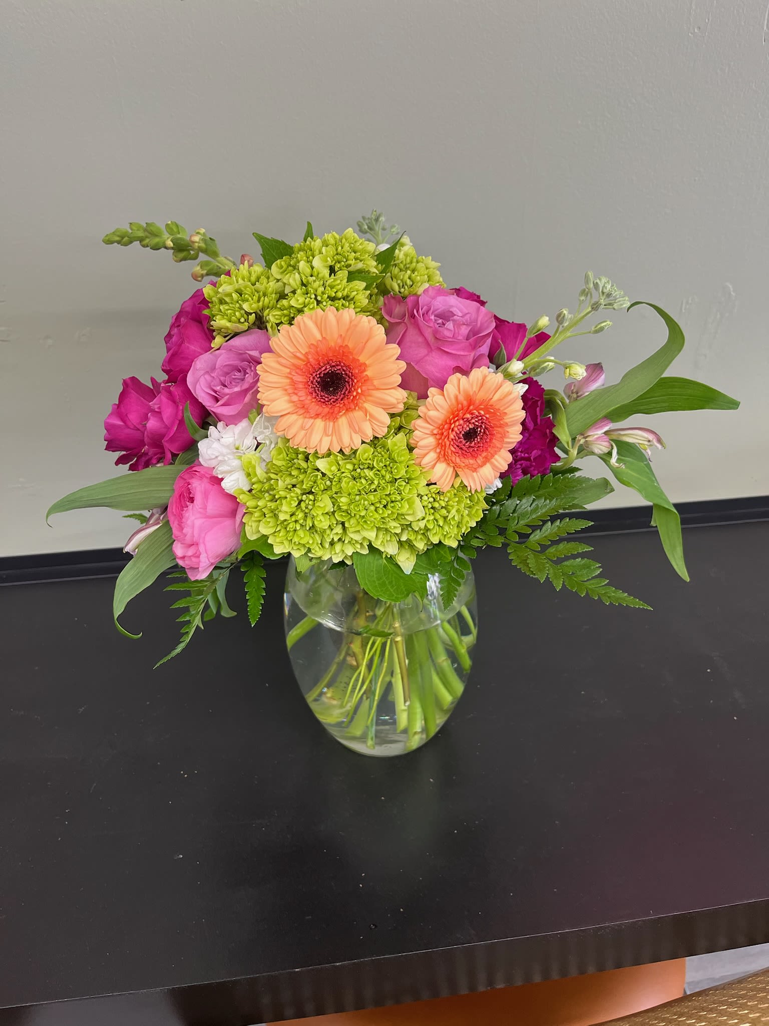Mixed pink and peach flowers arranged in a clear glass vase