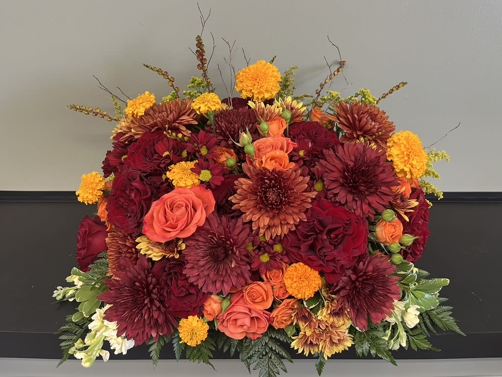 Large bouquet of red, orange, and yellow flowers in a low arrangement