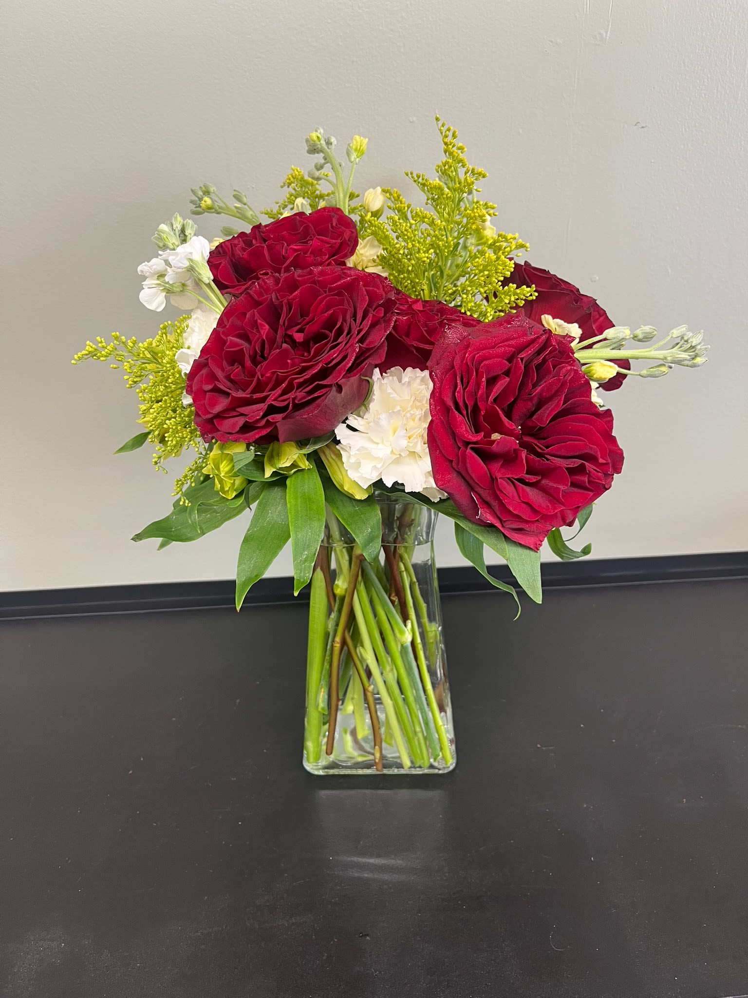 Red roses and white flowers in a clear glass vase
