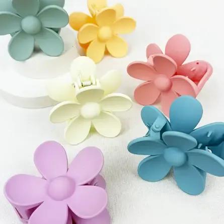 Pastel flower-shaped hair clips arranged on a white surface