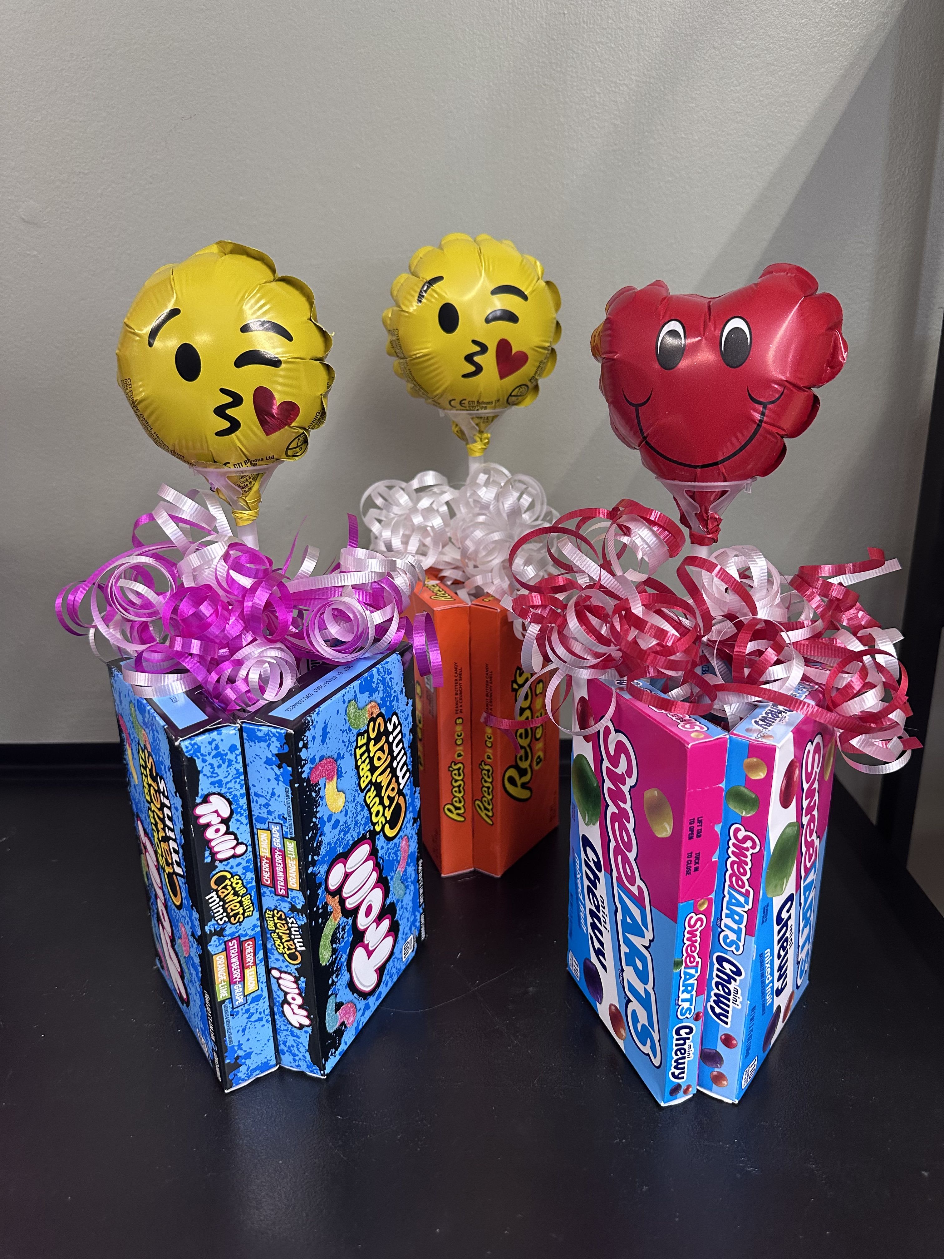Candy gift boxes topped with emoji balloons and curly ribbon