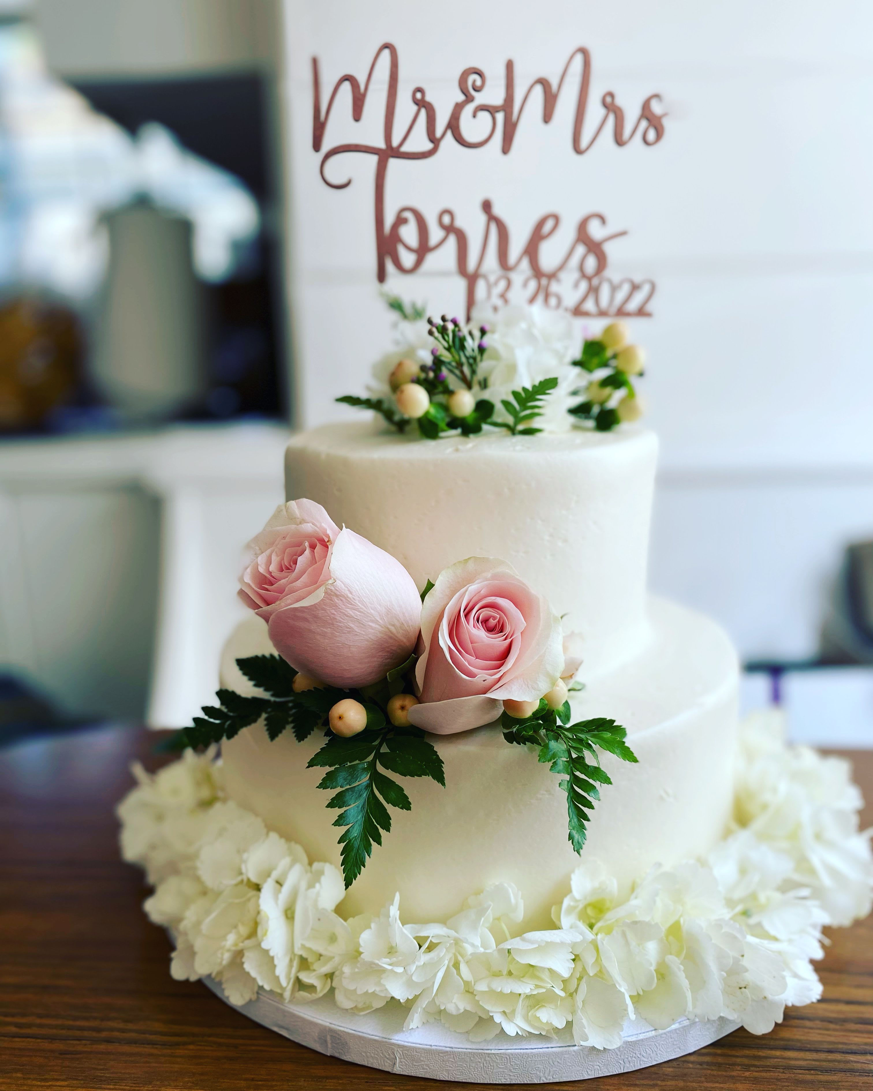 Two-tier white cake with pink roses and white flowers