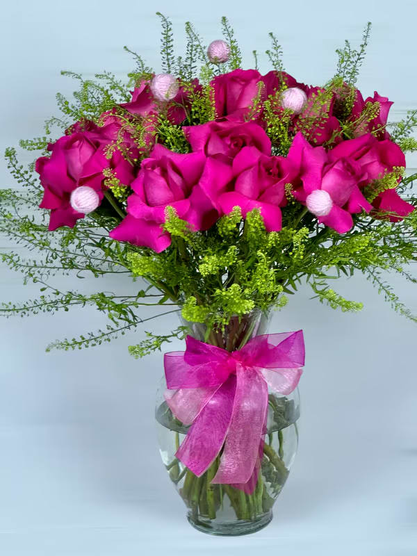 Bouquet of hot pink roses in a glass vase with a pink ribbon