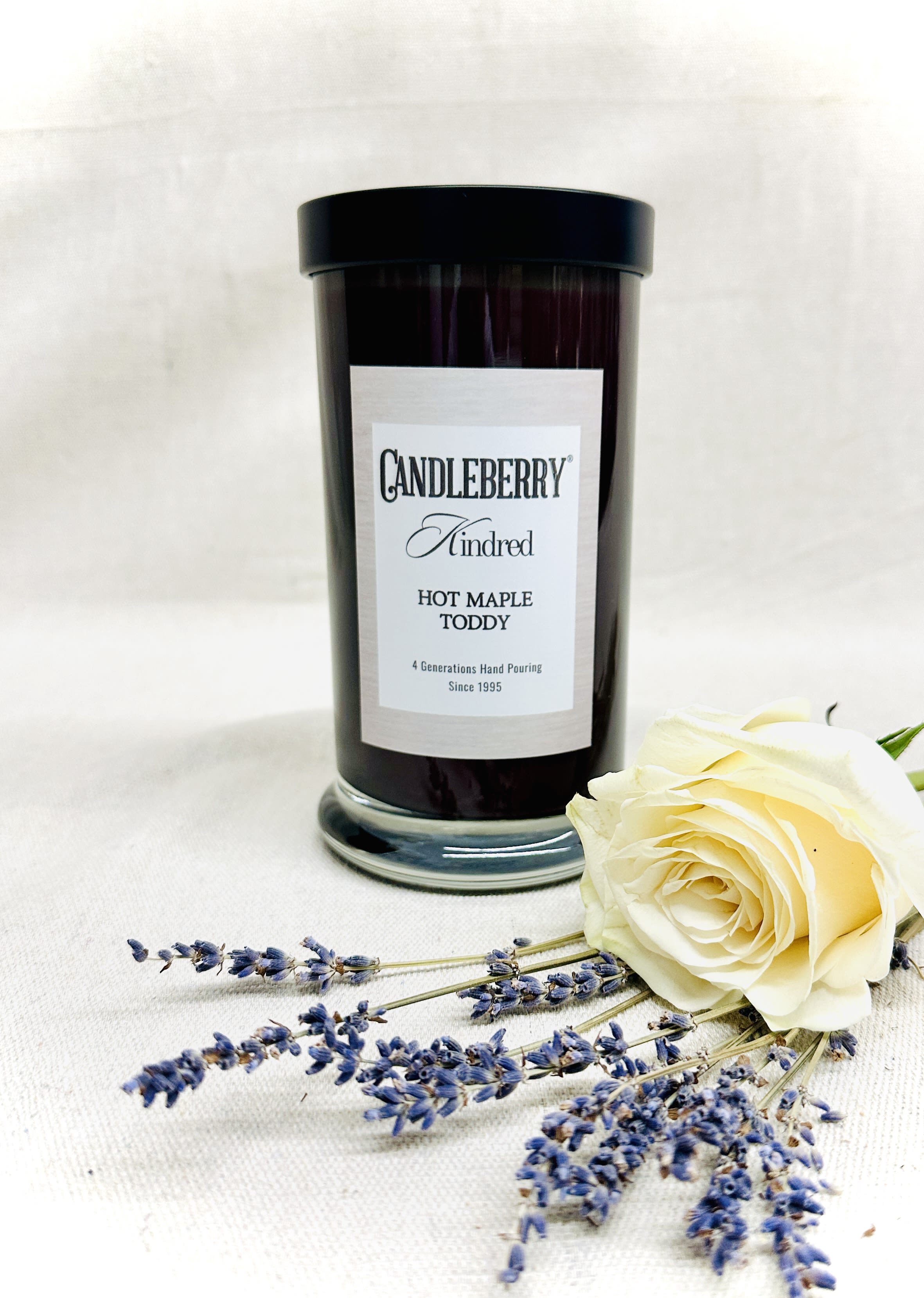 Black candle jar with a cream rose and lavender sprigs