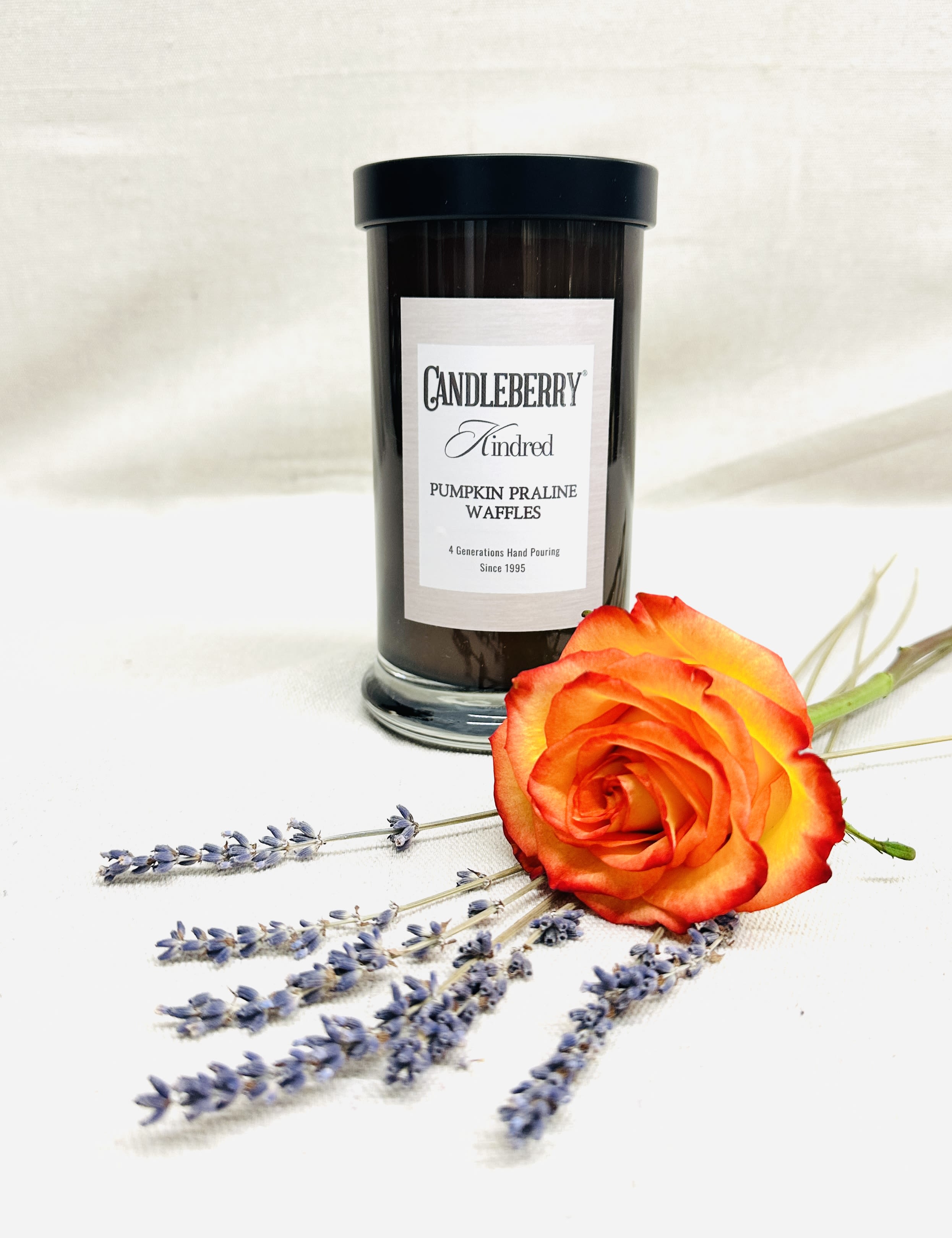 Orange rose beside a black candle jar with lavender sprigs