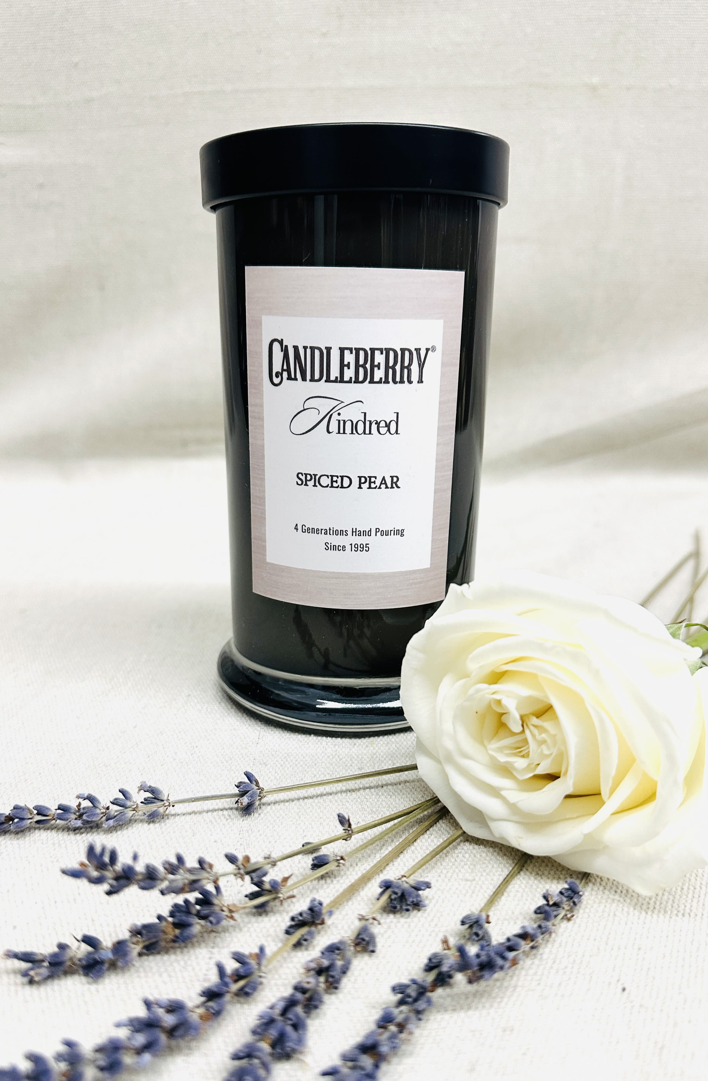 Black candle jar with a white rose and lavender sprigs
