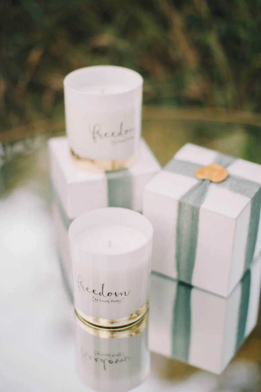 Three white candles and two white gift boxes with green ribbon