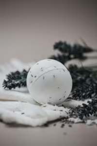 White spherical candle with dark specks on a soft surface