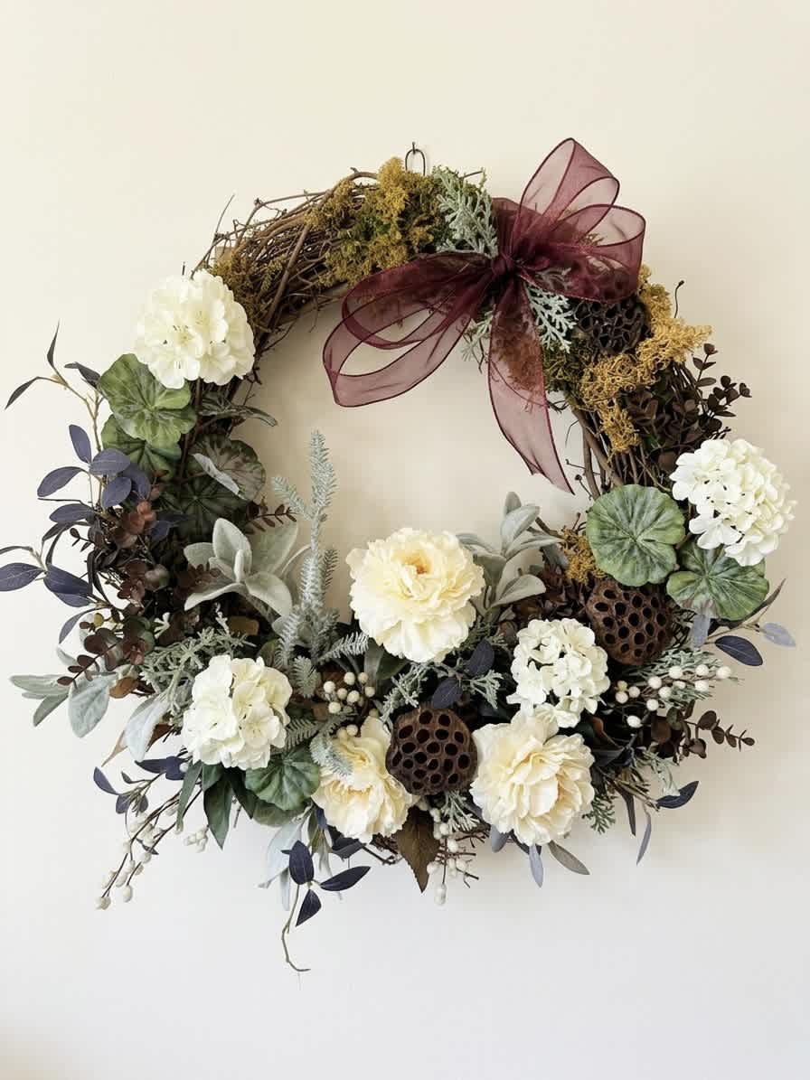 Floral wreath with cream blooms and a burgundy ribbon bow
