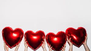 Hands holding four red heart-shaped balloons against a white background