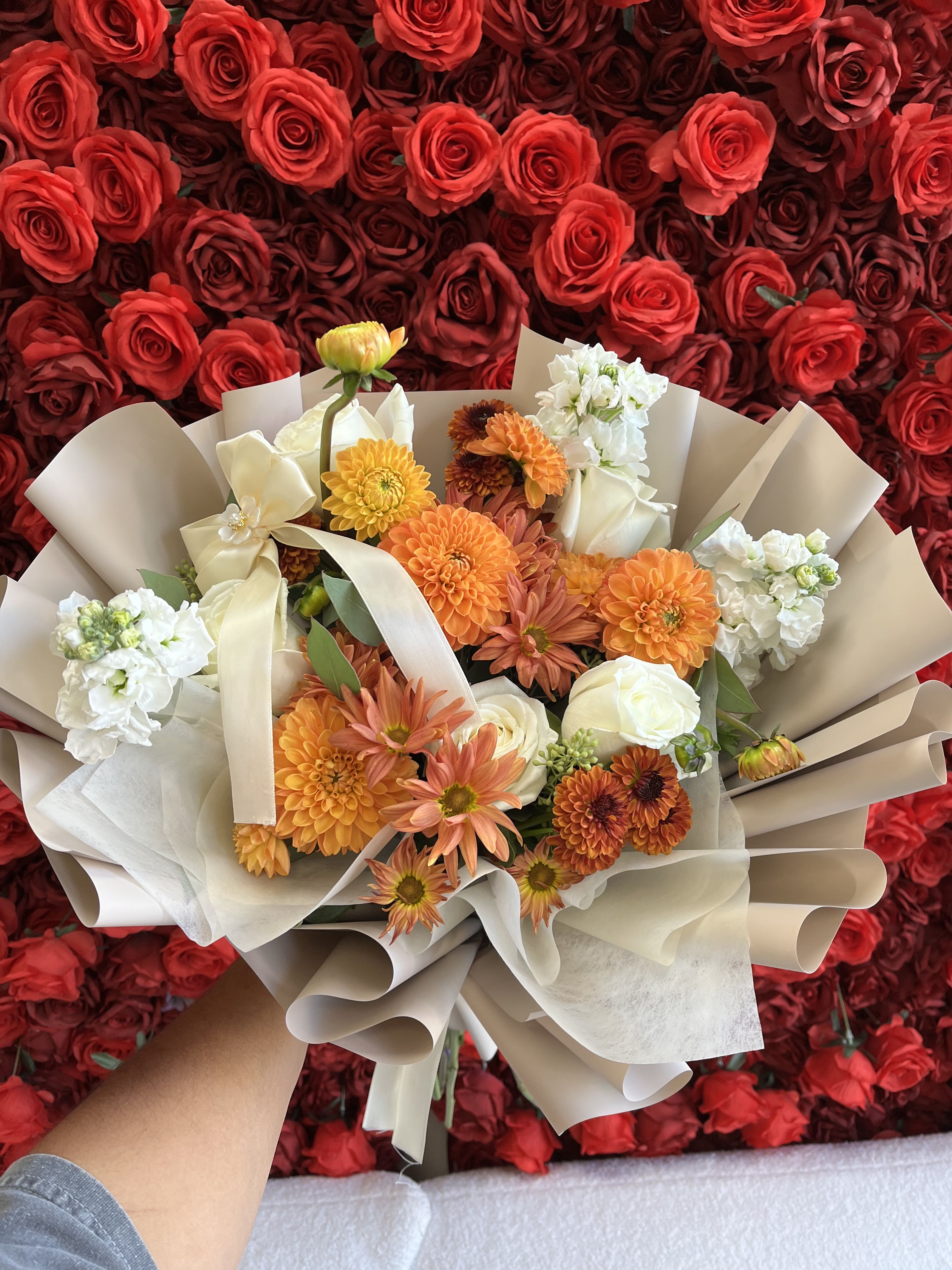 Bouquet of orange, white, and cream flowers wrapped in beige paper