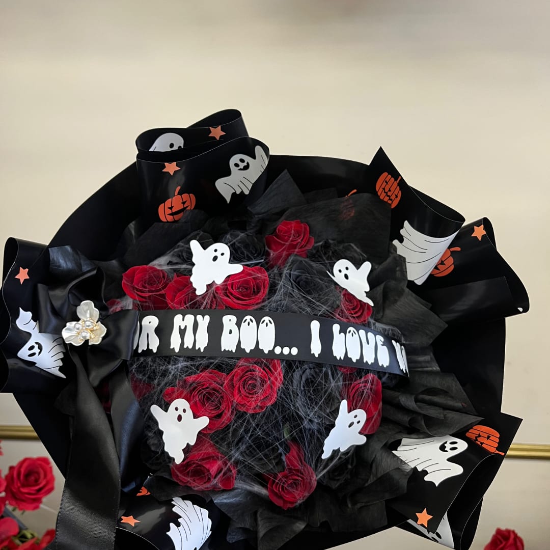 Halloween-themed bouquet of red roses wrapped in black paper with ghost decorations