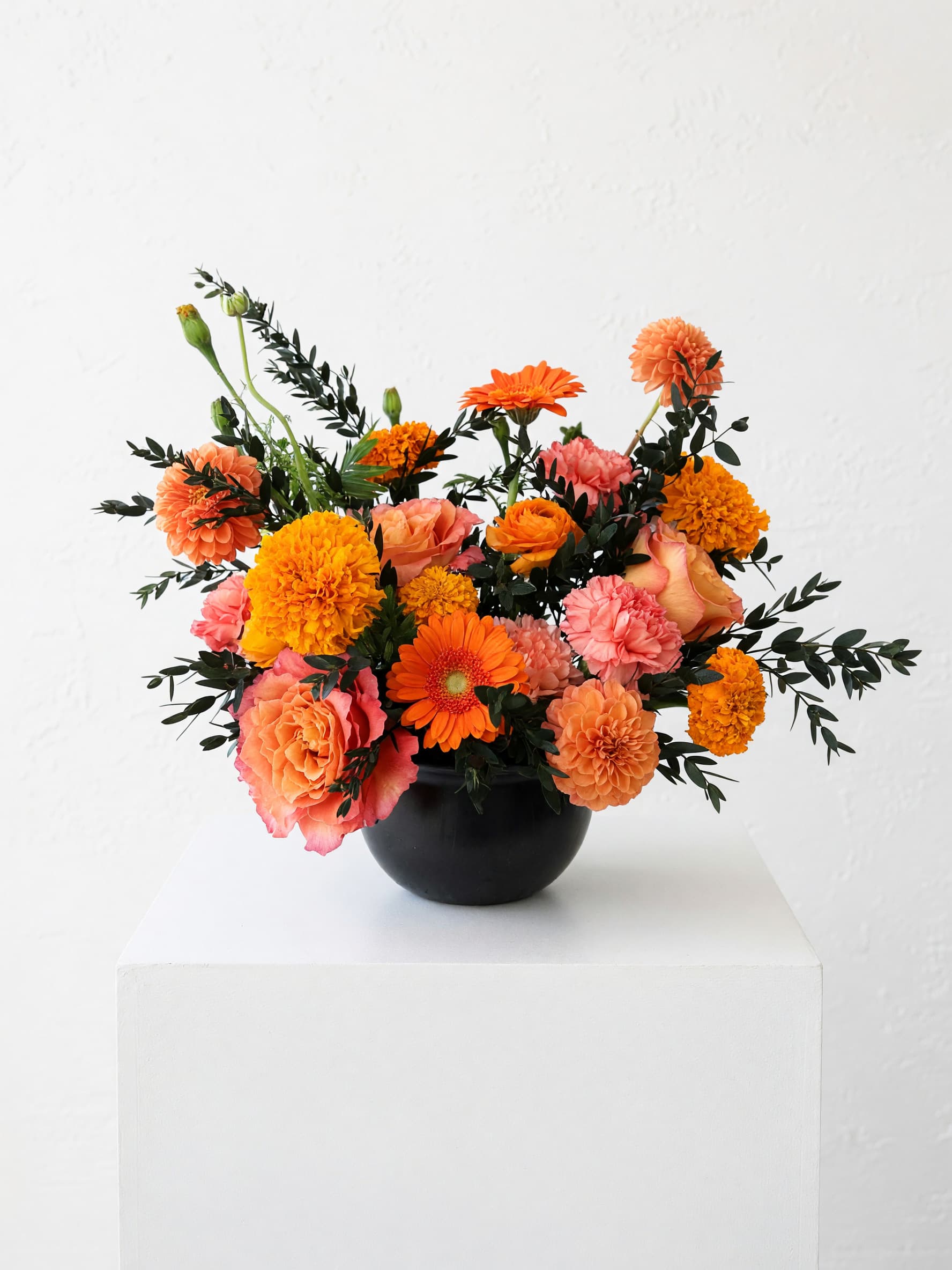 Orange and pink mixed bouquet in a black vase