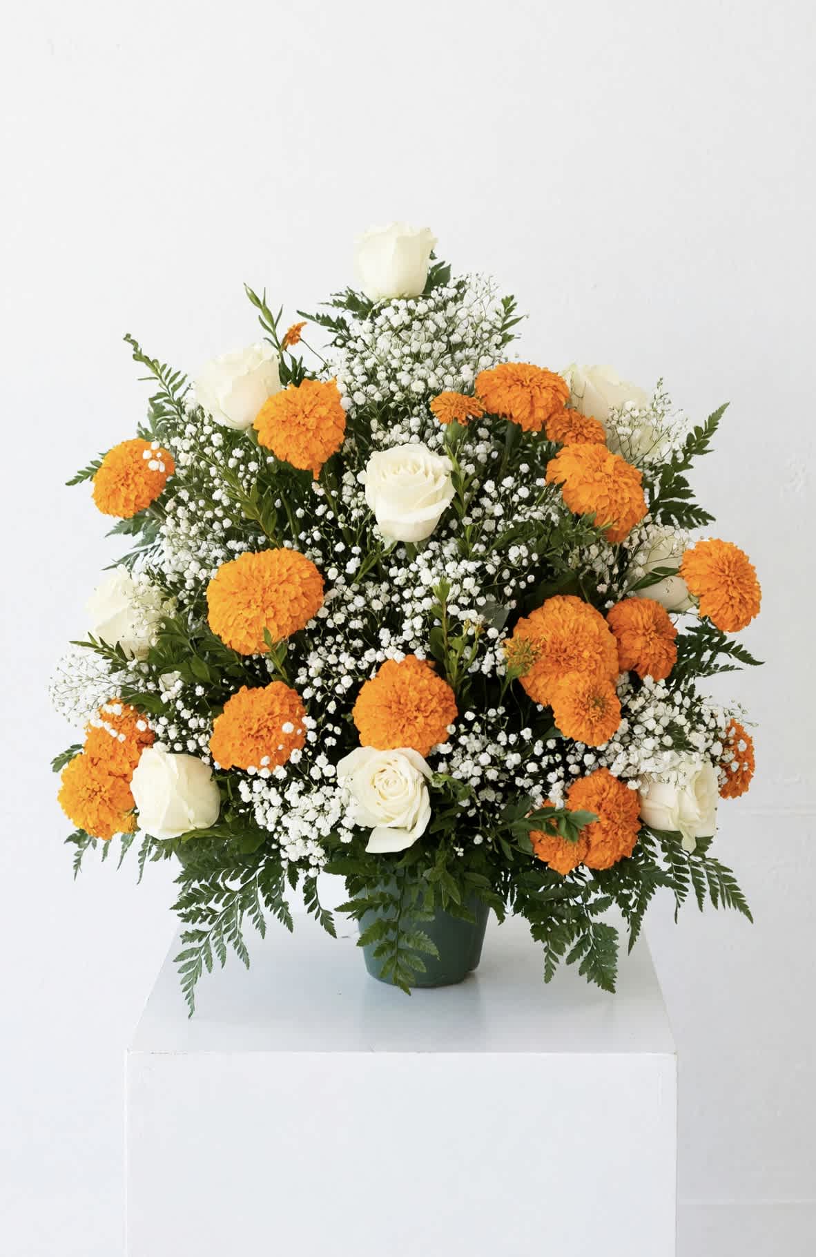 White roses and orange marigolds in a green vase