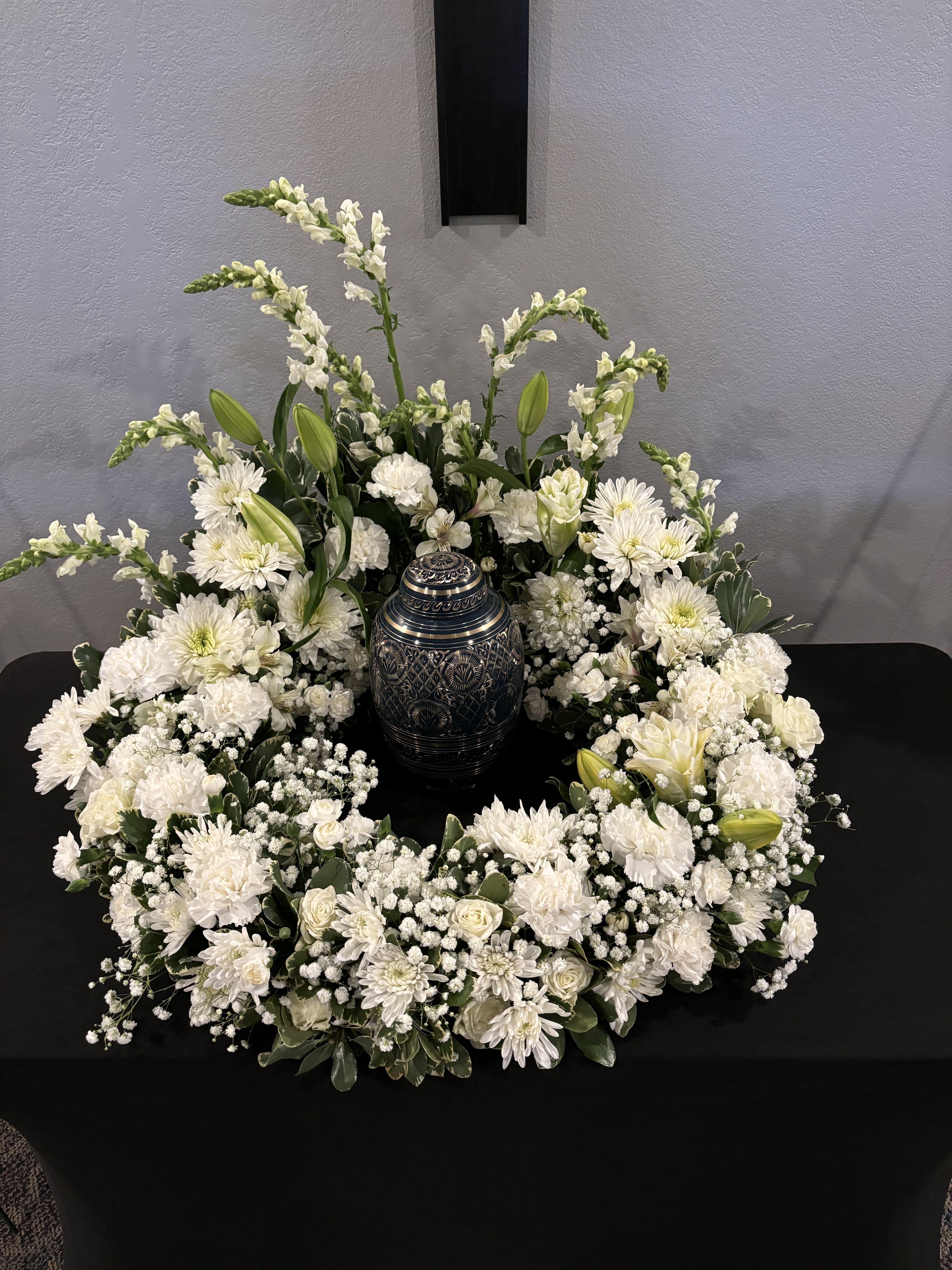 White floral wreath around a decorative urn