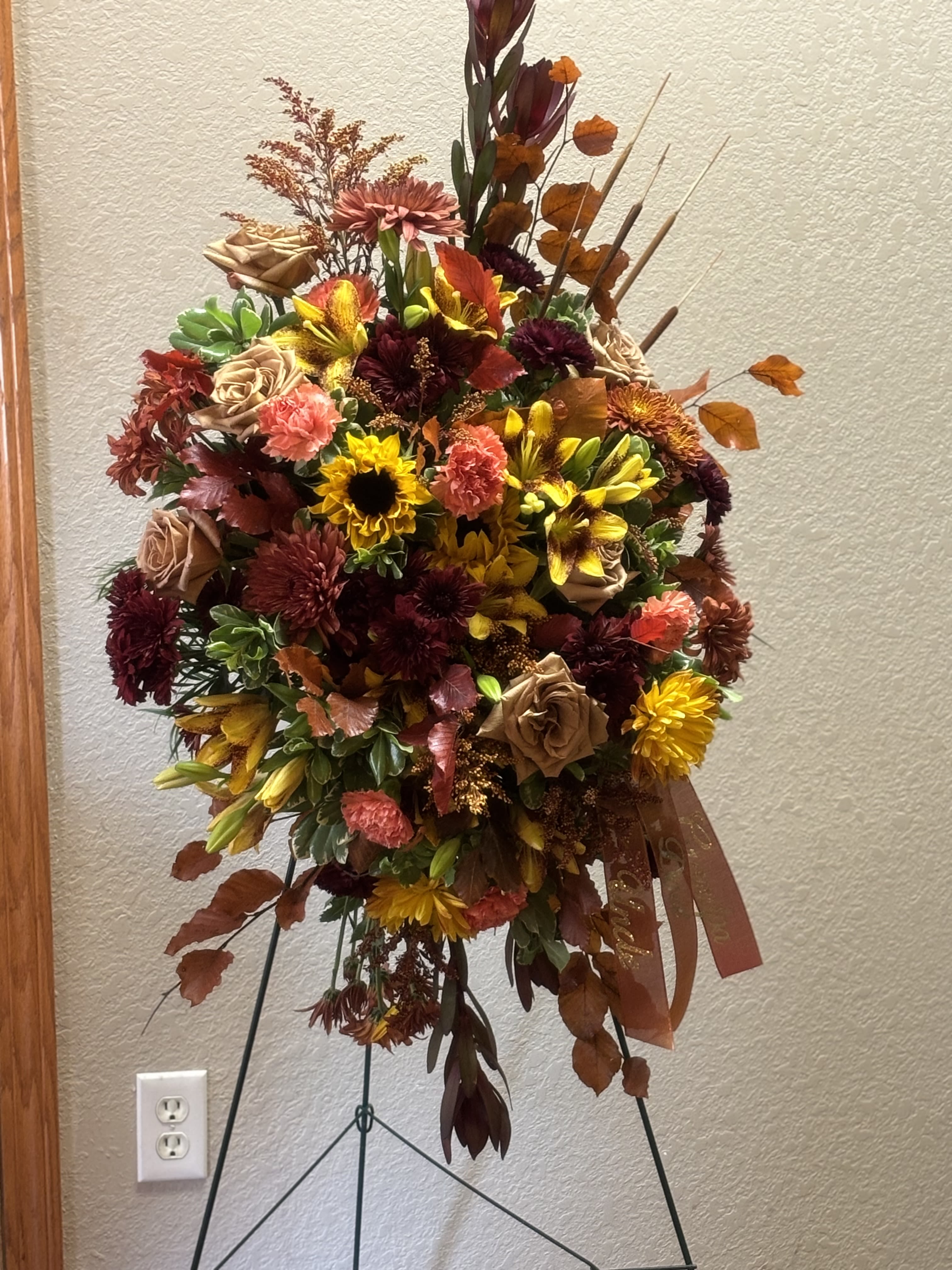 Large autumn floral spray on a stand with sunflowers, roses, and mums