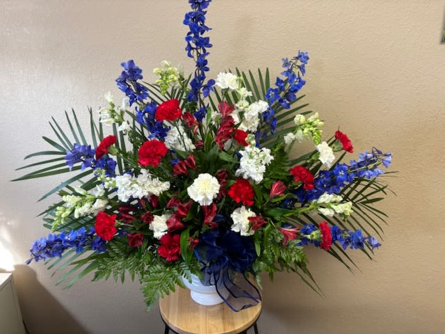Large red, white, and blue floral arrangement in a white vase