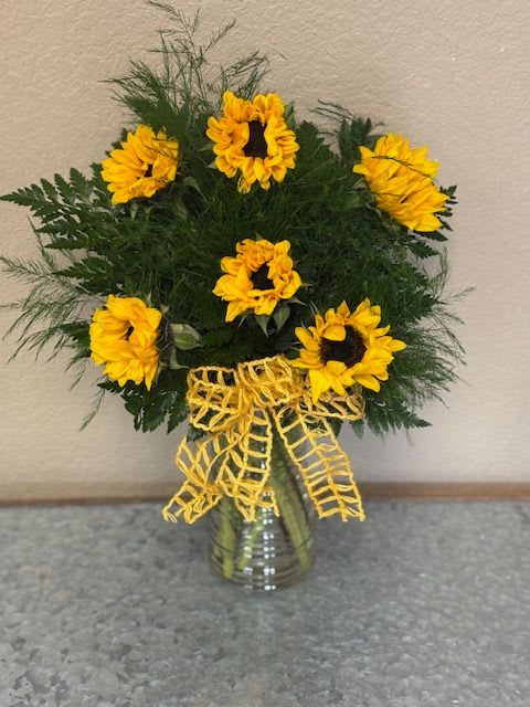 Sunflower arrangement in a glass vase with a yellow ribbon