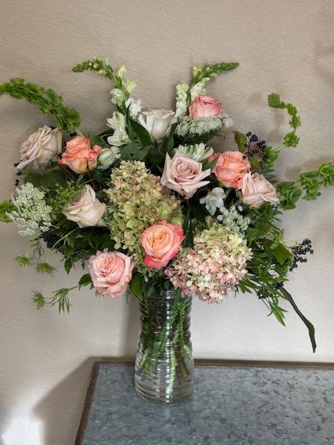 Pink and white roses with hydrangeas in a clear glass vase