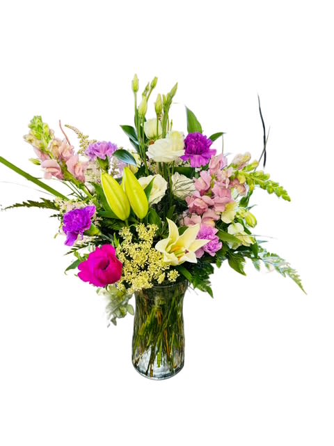 Mixed bouquet of lilies, orchids, and pink flowers in a glass vase