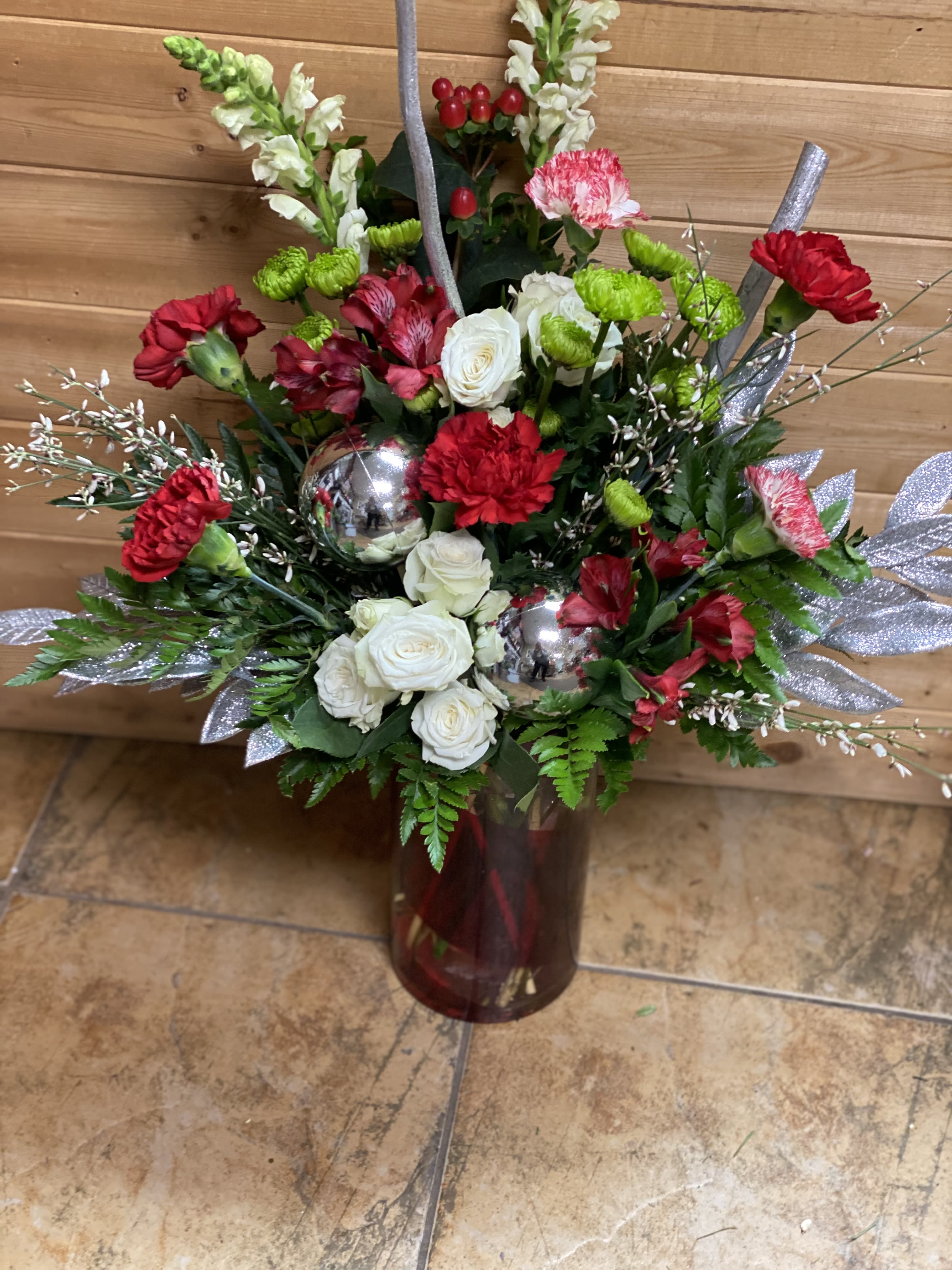 Red and white floral arrangement in a burgundy vase with silver accents