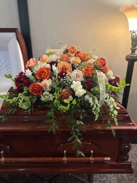 Large floral spray on a casket with orange and white roses