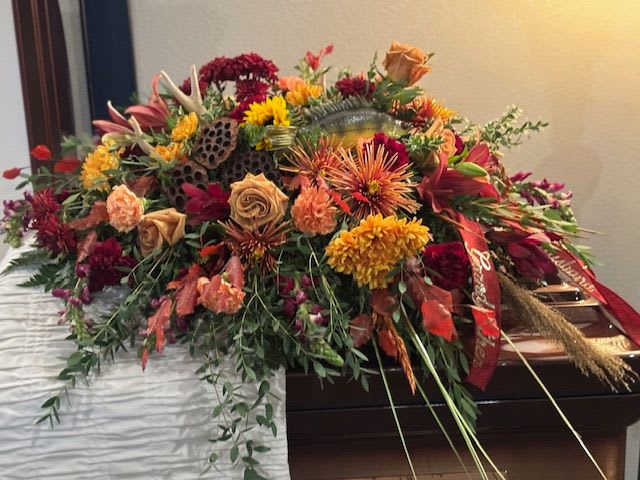 Large casket spray with orange, red, and yellow flowers