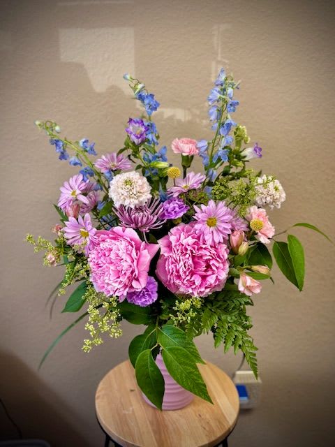 Pink peonies and purple-blue mixed flowers in a pink vase