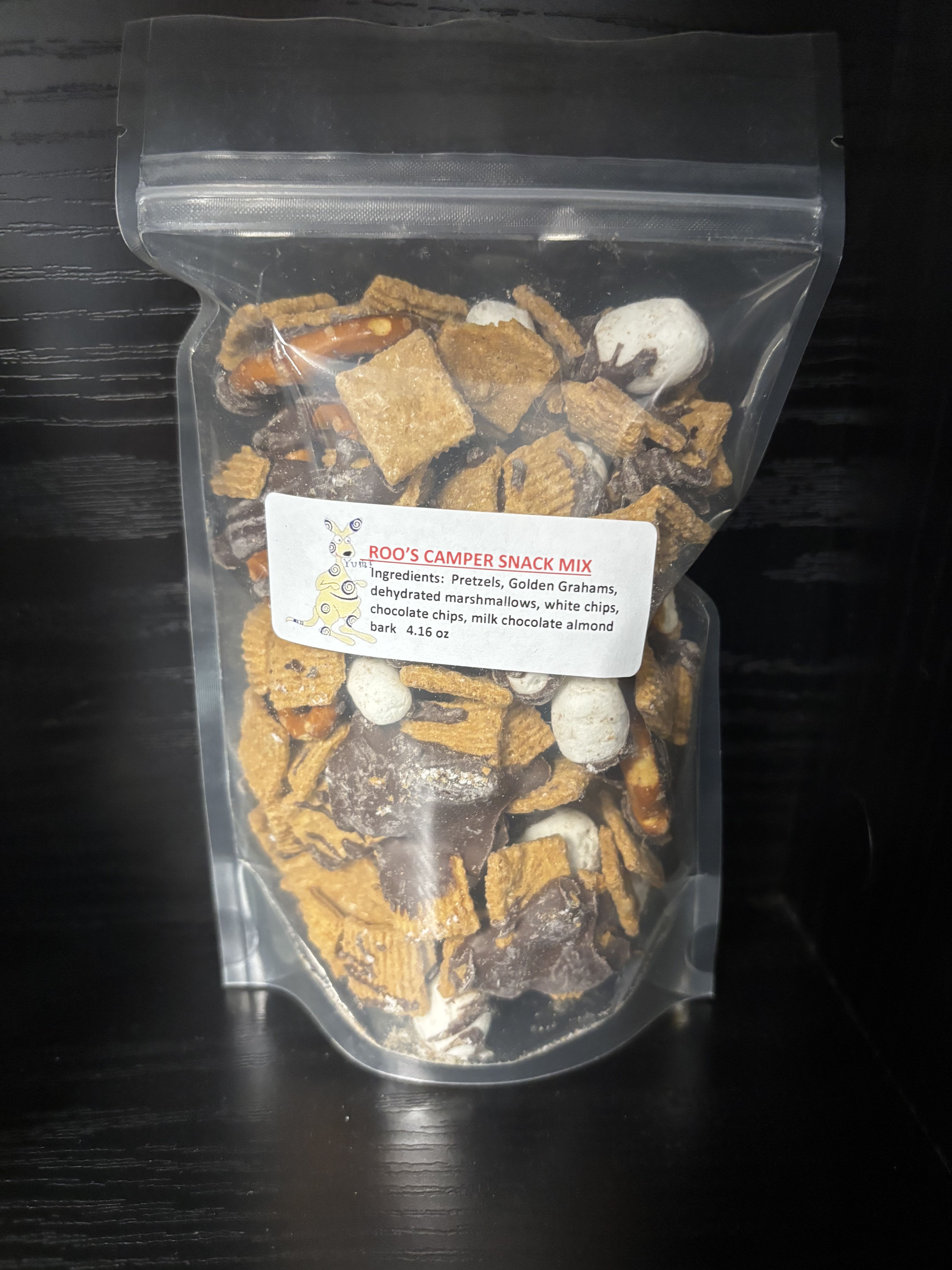 Clear bag of camper snack mix with pretzels, cereal, marshmallows, and chocolate pieces