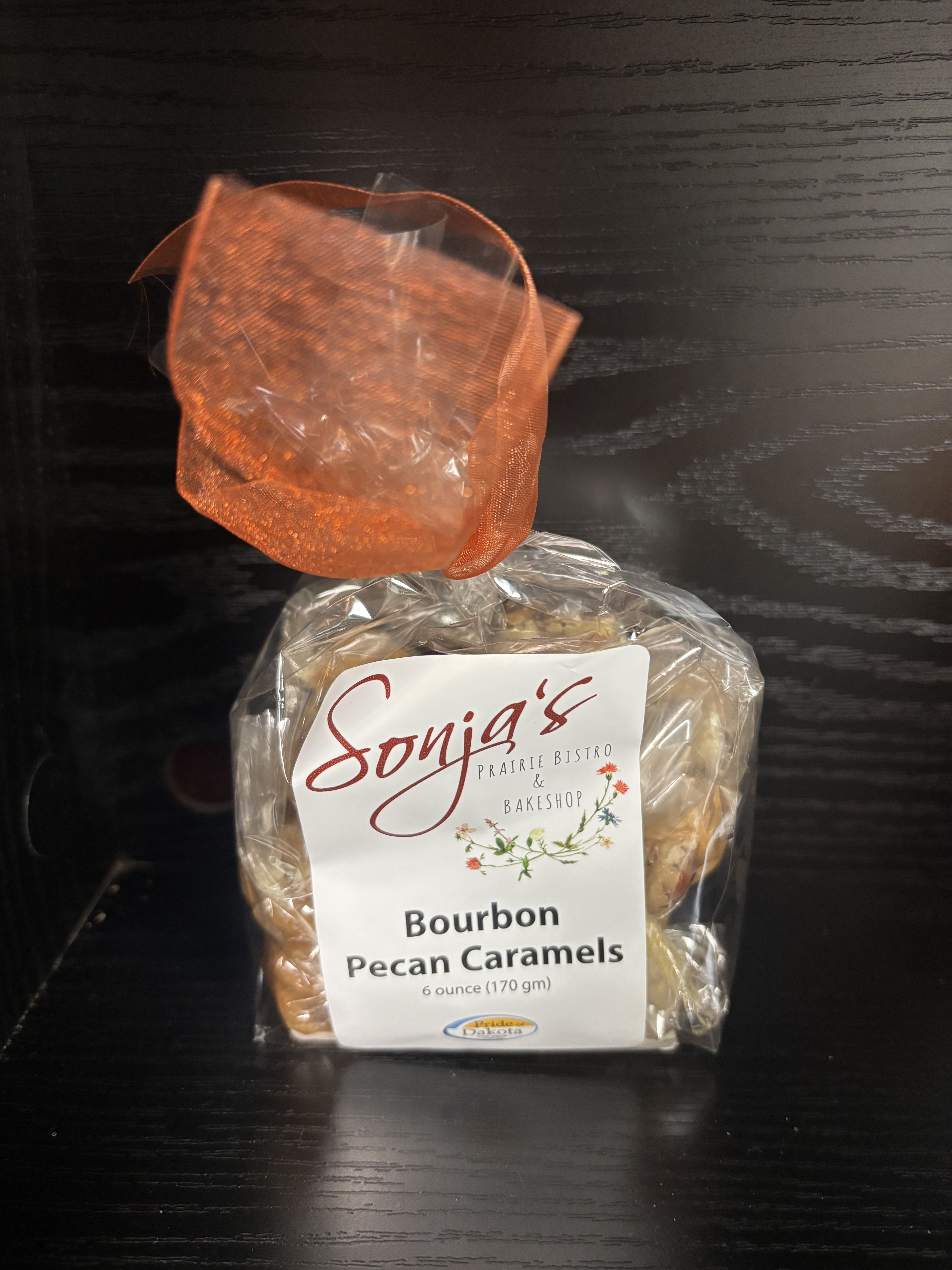 Bag of bourbon pecan caramels tied with orange ribbon