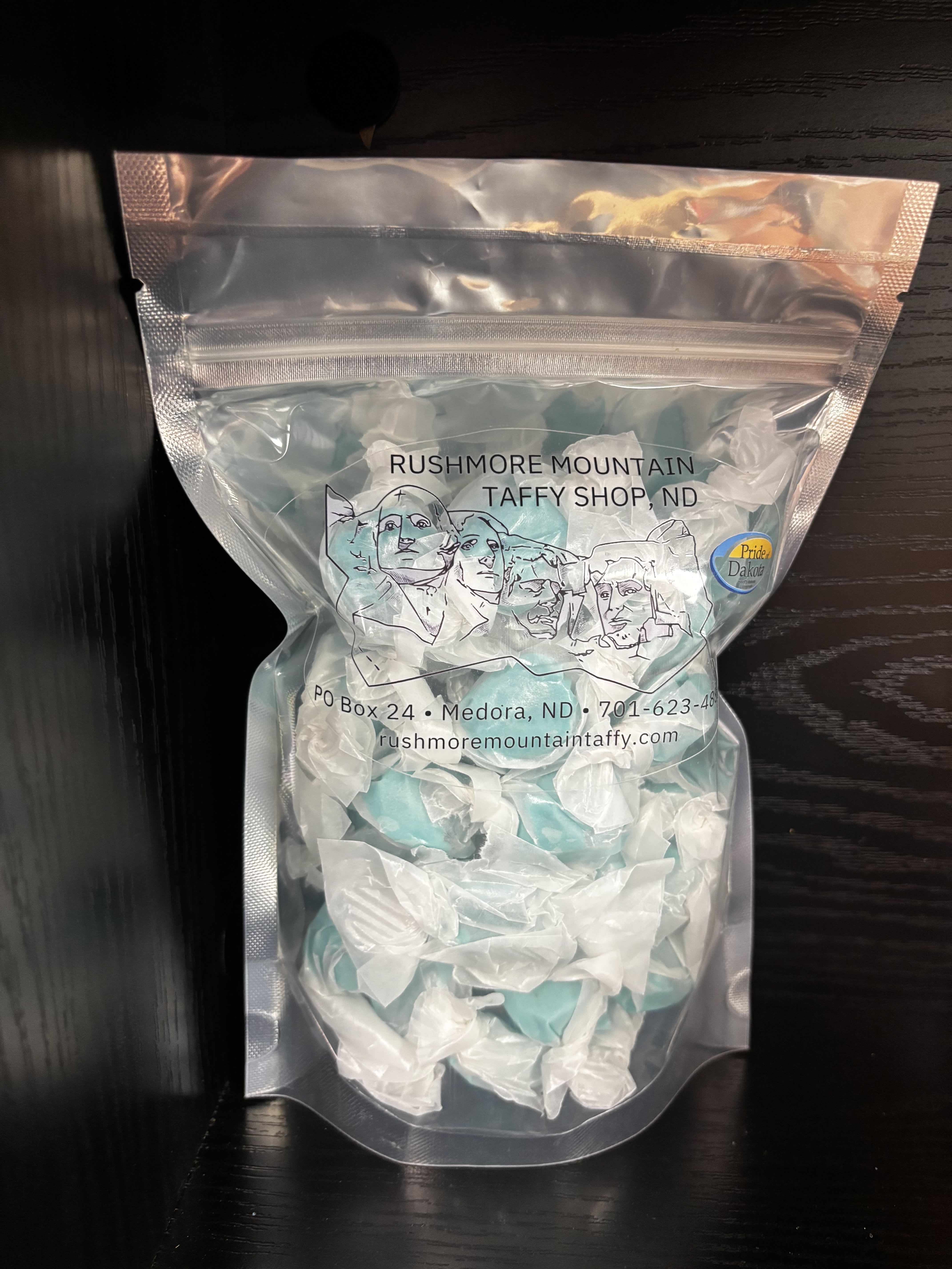 A clear bag of blue and white taffy candy with printed text