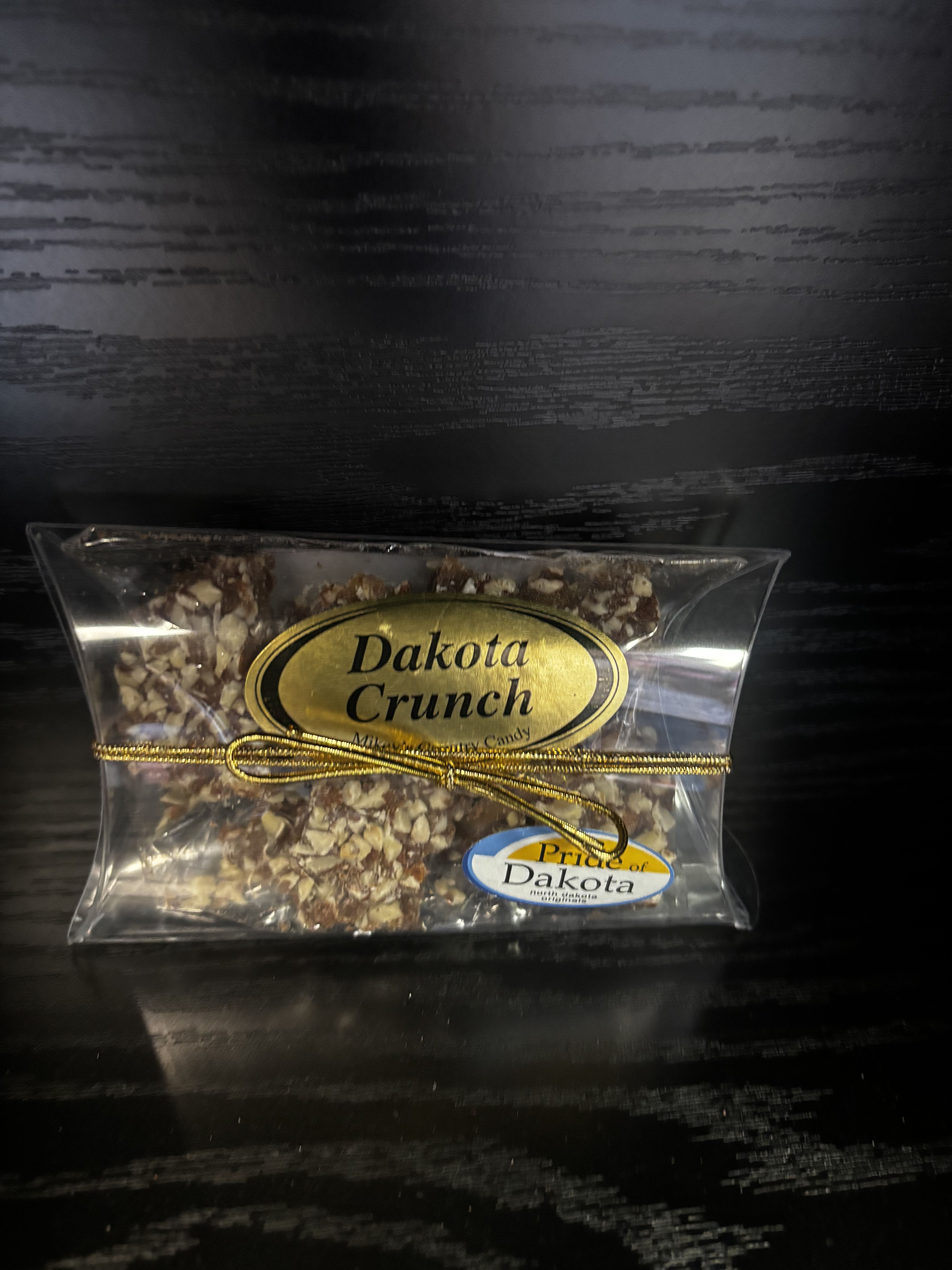 Clear bag of Dakota Crunch candy tied with a gold ribbon