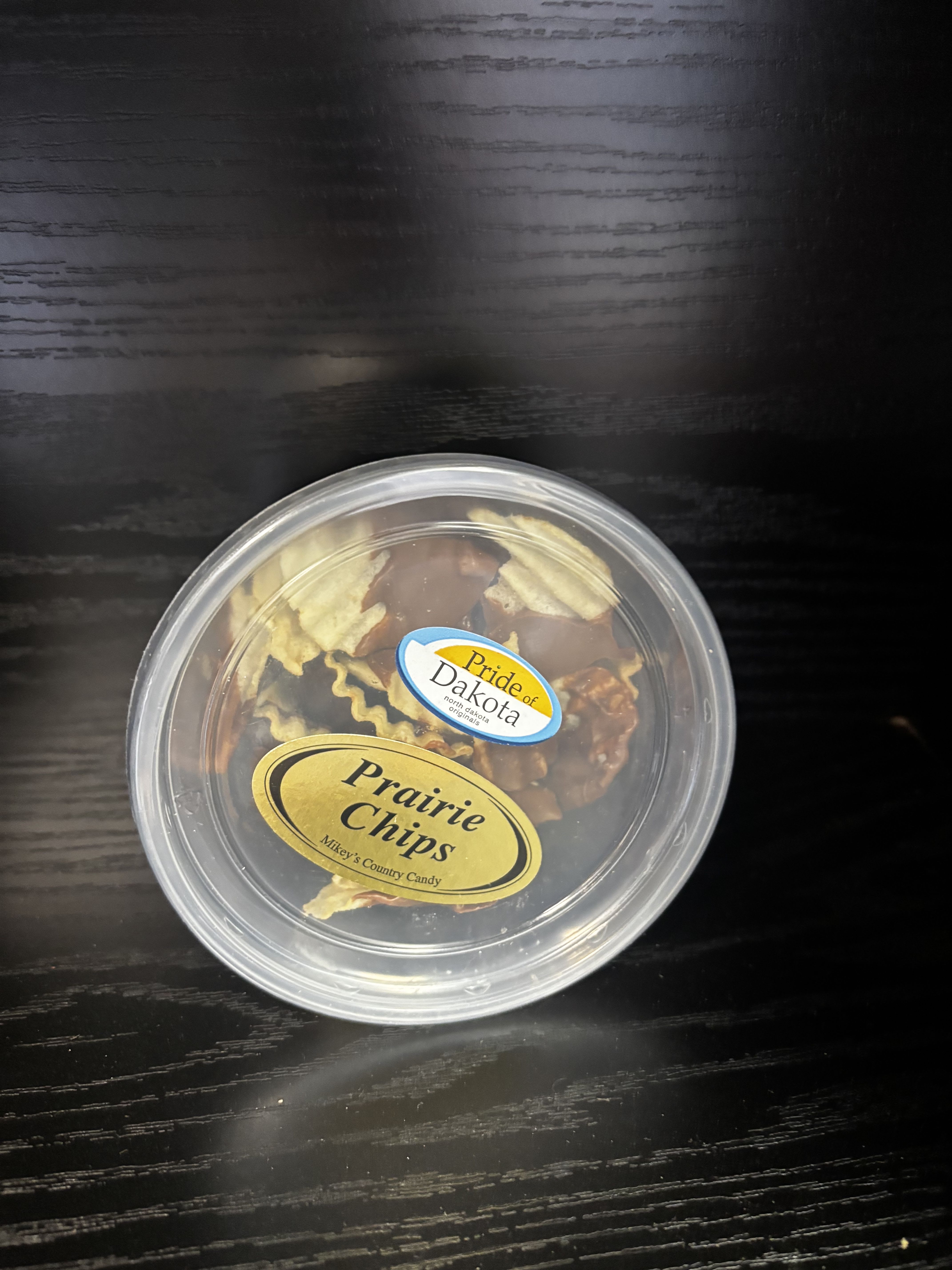 Round plastic tub of assorted candy on a dark table