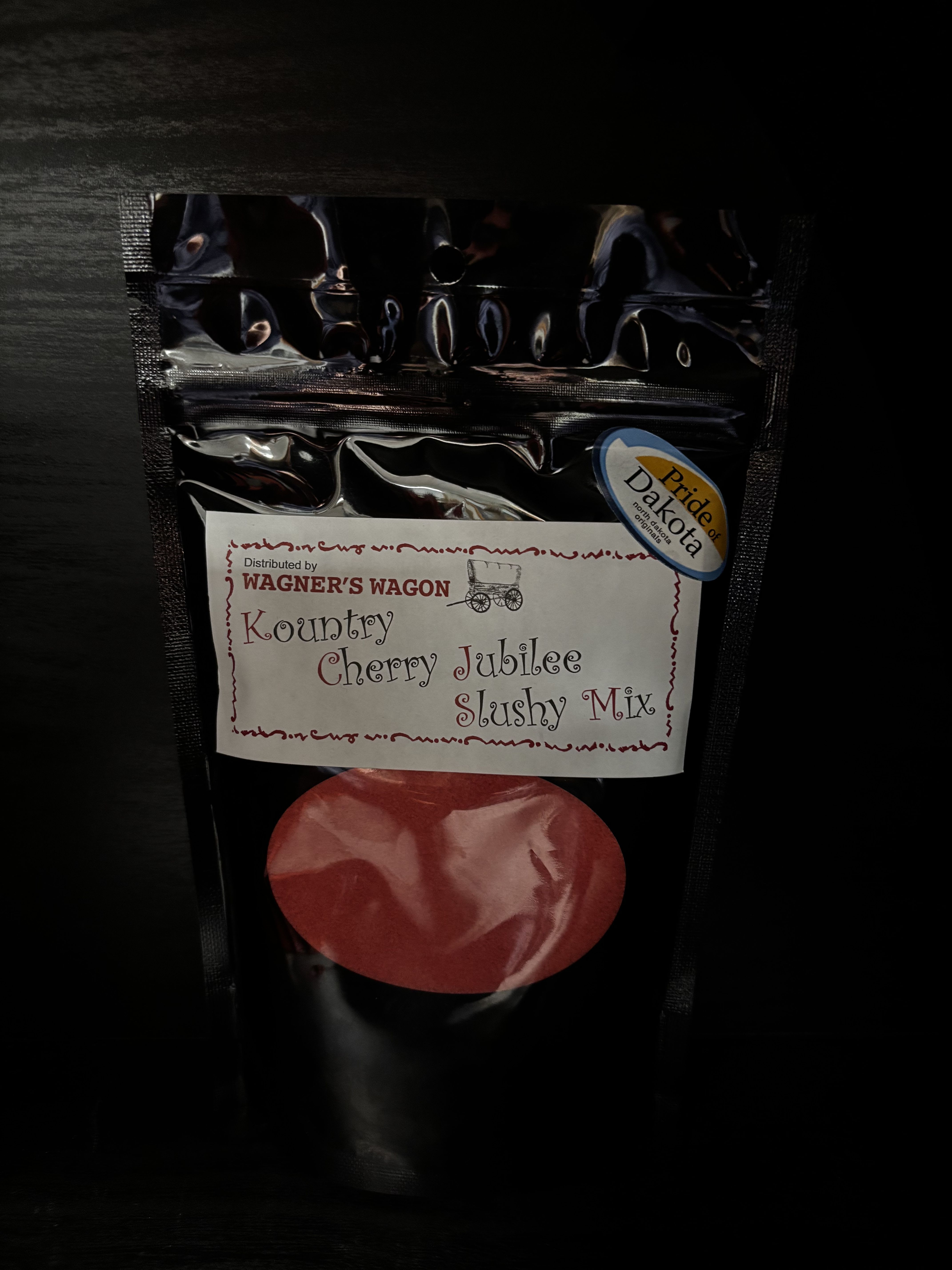 Black pouch of cherry jubilee slushy mix with a red fruit graphic