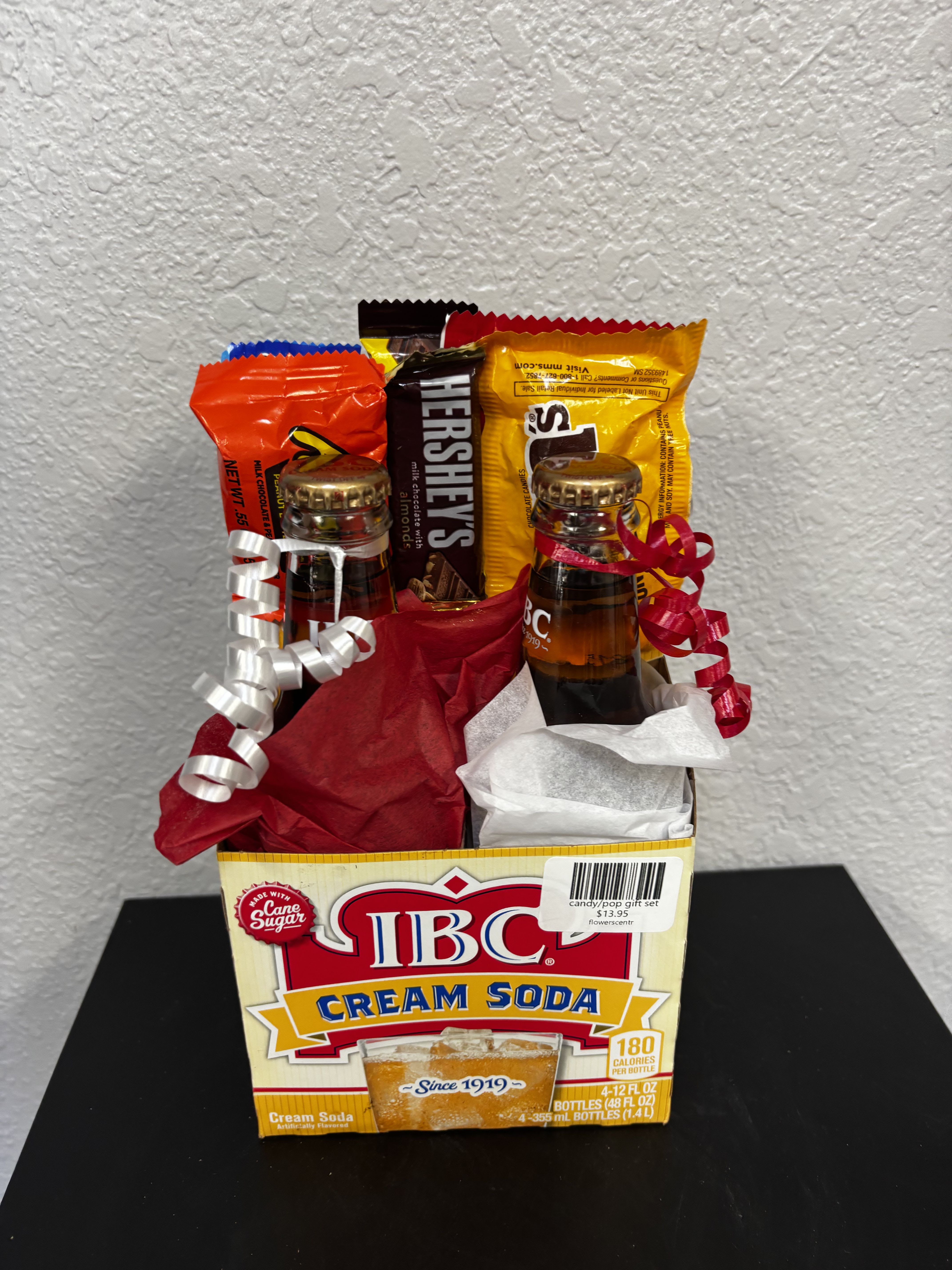 Gift basket with candy bars and two small soda bottles in a cream soda box
