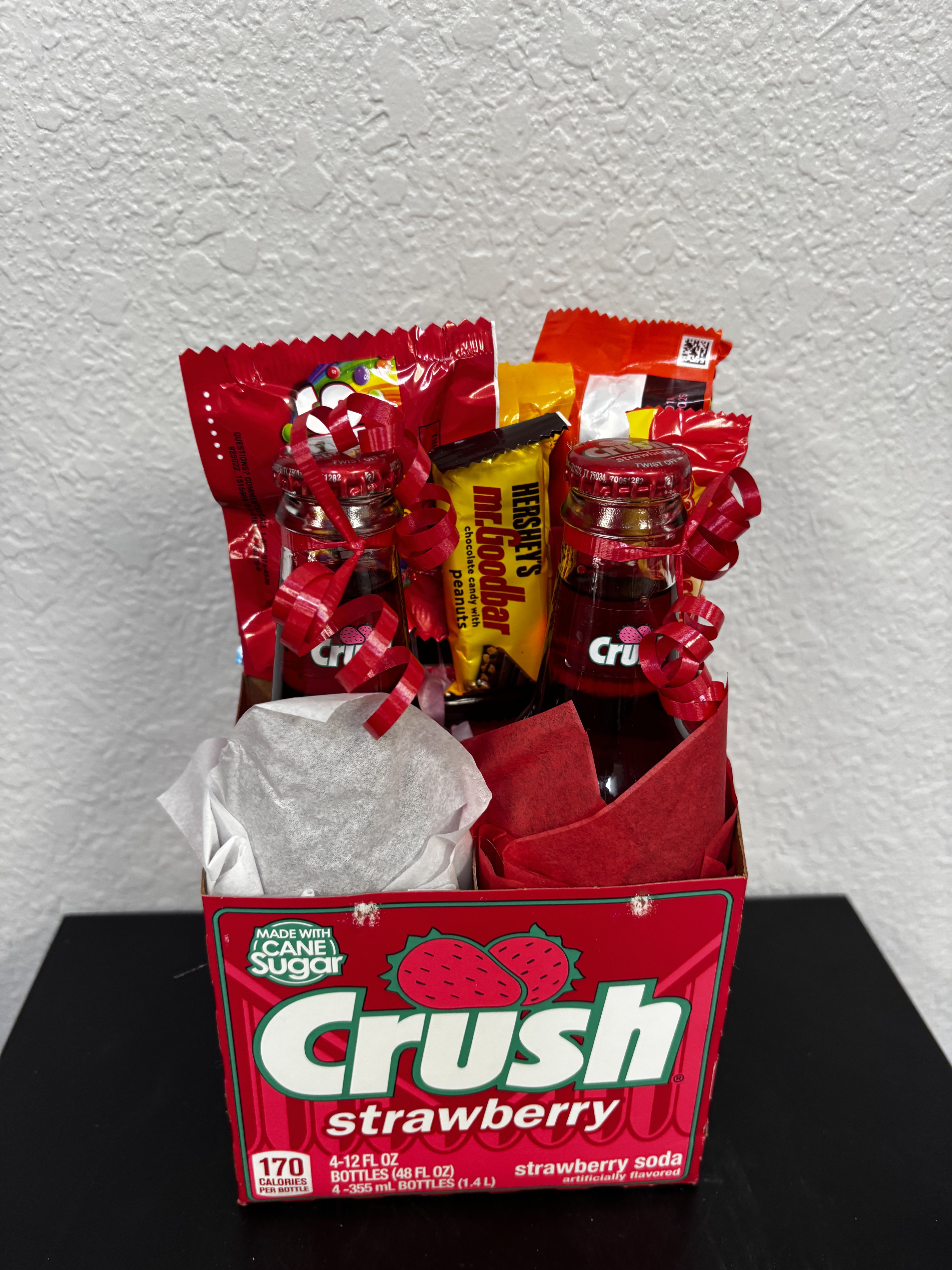 Gift box with soda bottles and candy bars wrapped in red ribbons