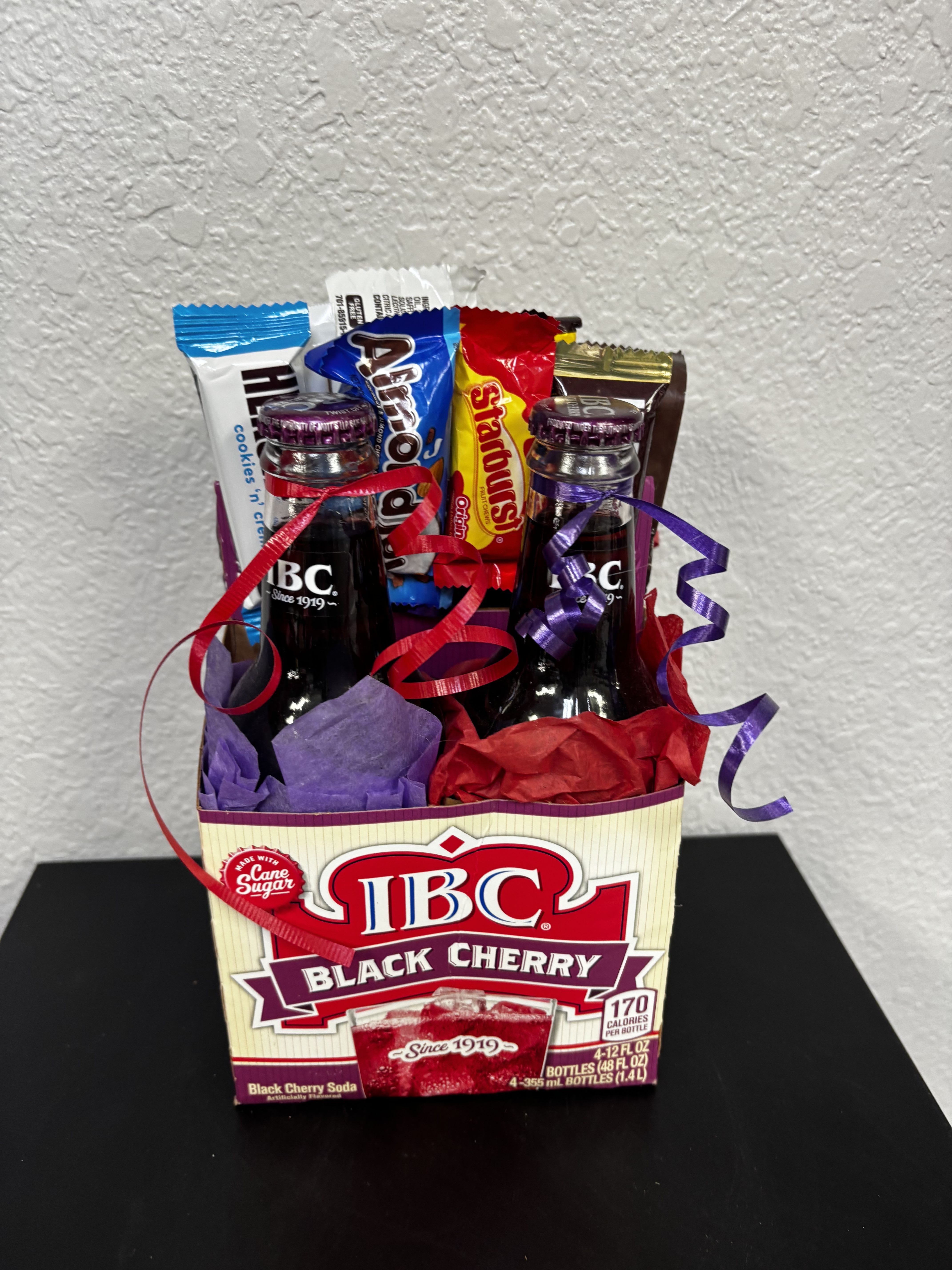 Gift basket with soda bottles and candy bars wrapped in colorful tissue and ribbons
