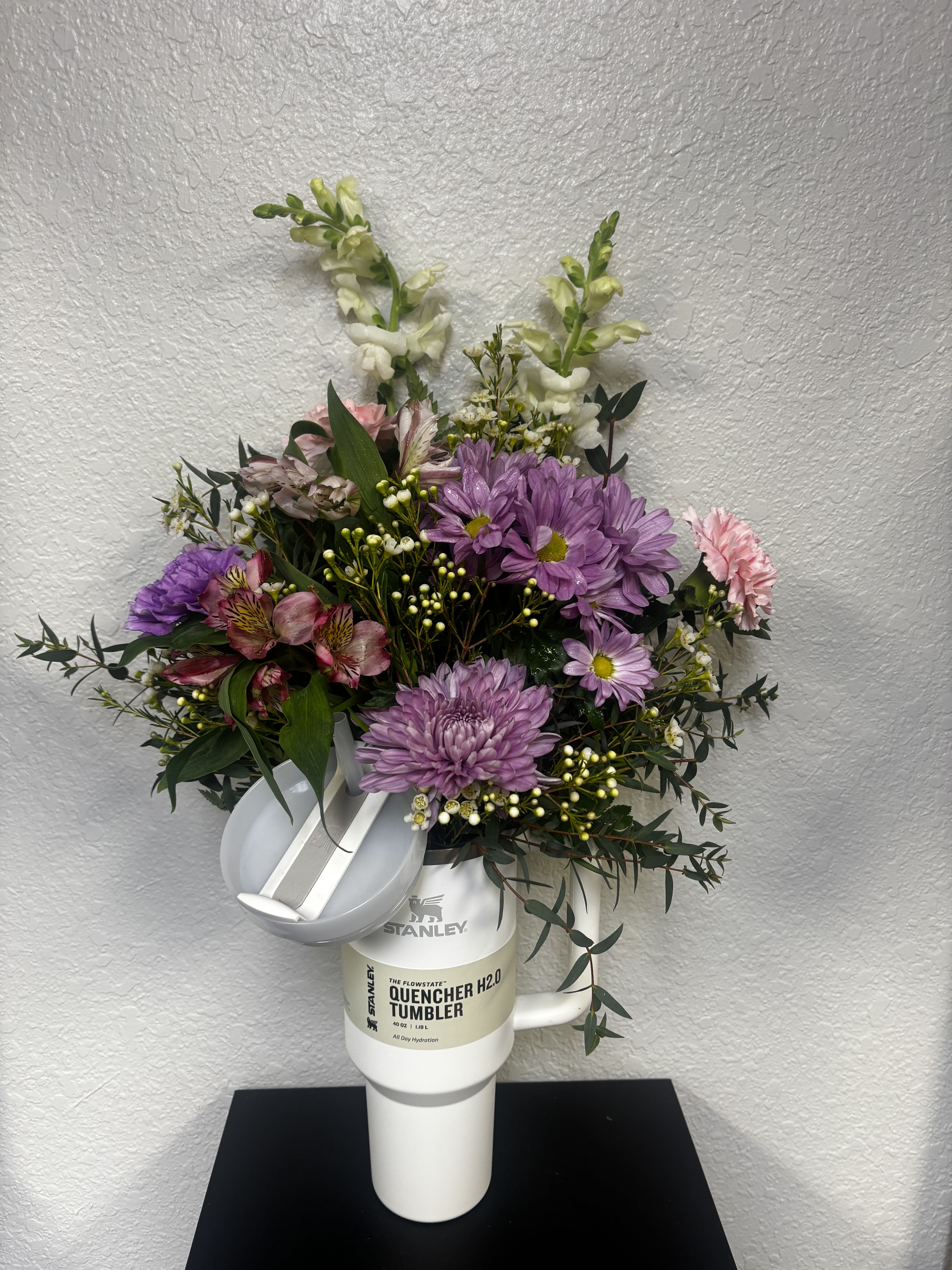 Bouquet of purple and pink flowers arranged in a white tumbler