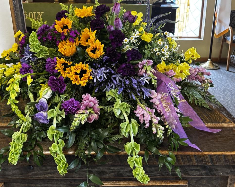 Large casket spray with yellow, purple, and pink flowers