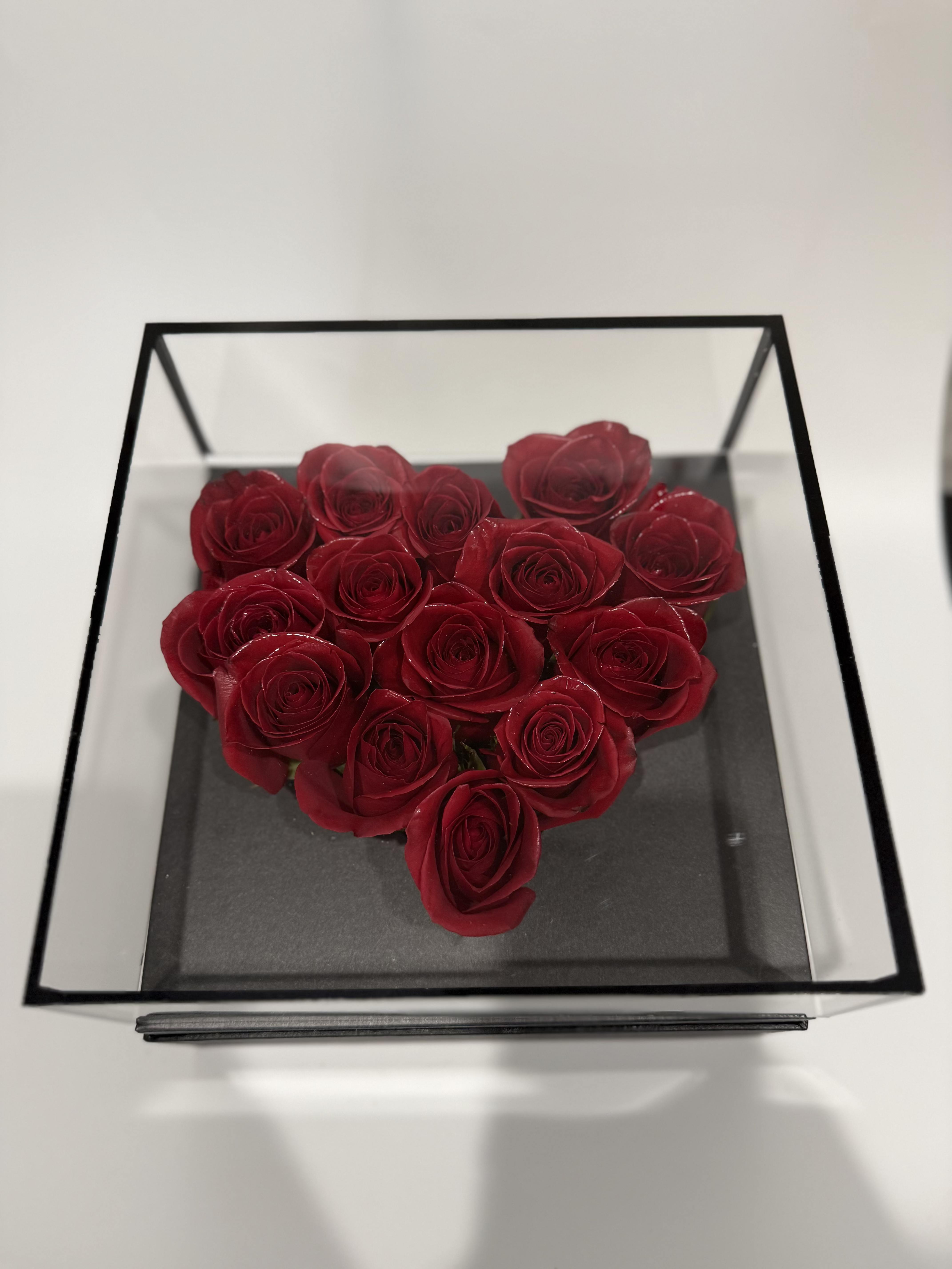 Heart-shaped arrangement of red roses in a clear square box