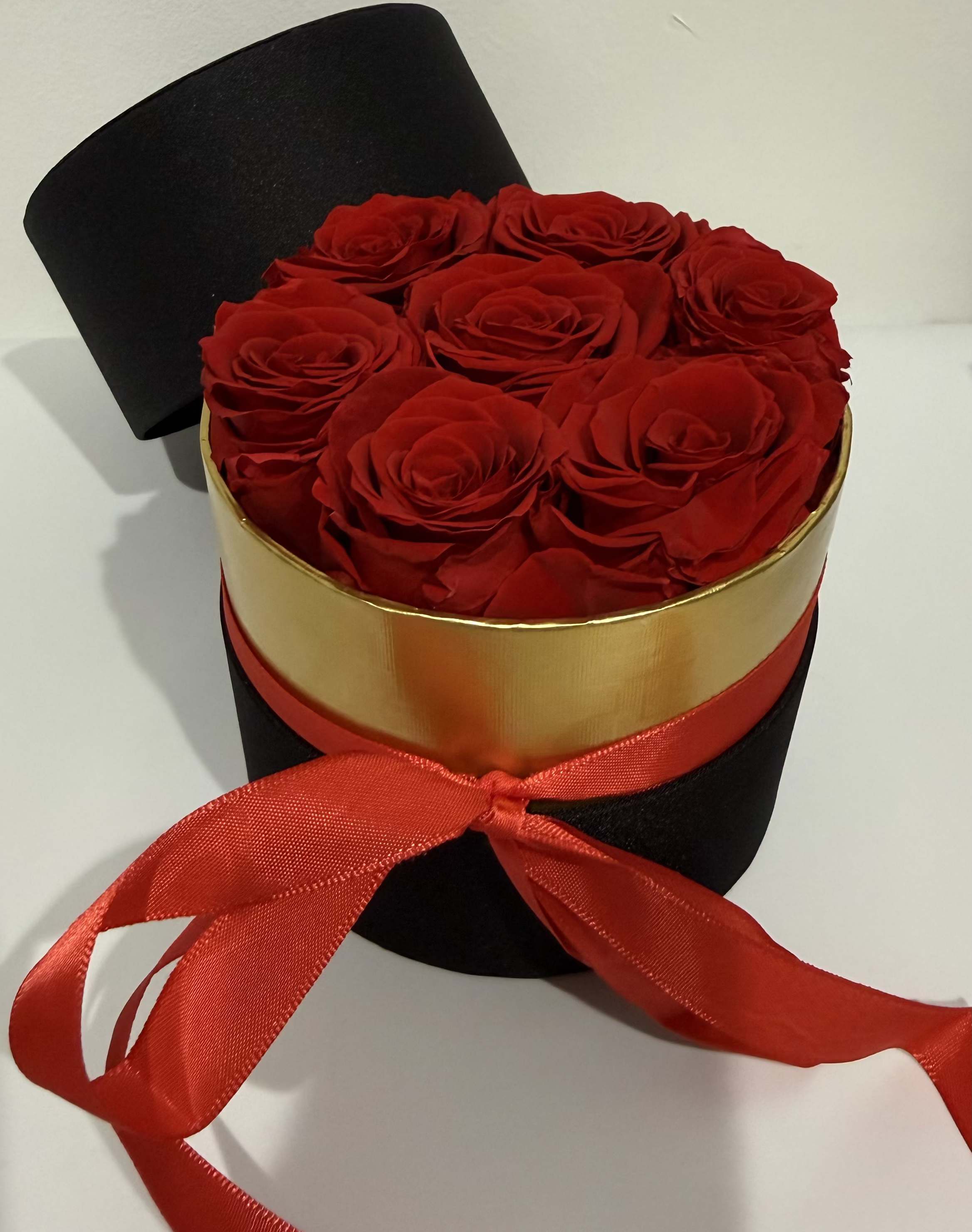Red roses in a black round box with a red ribbon