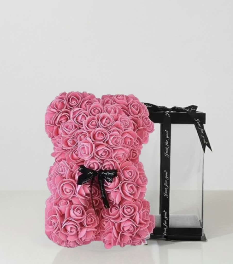 Pink rose teddy bear with a black ribbon on a display stand