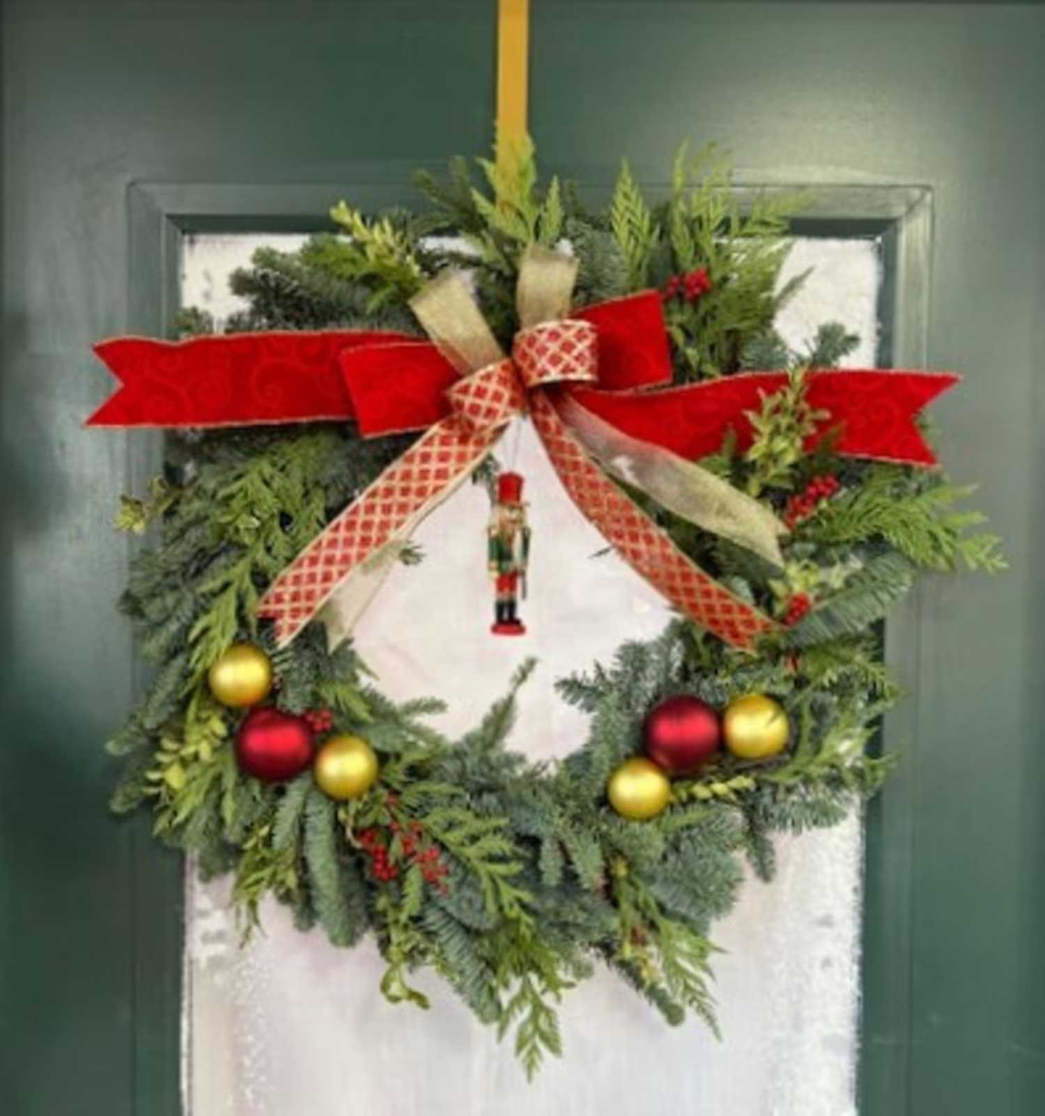 Christmas wreath with red and gold ribbon and ornaments on a door