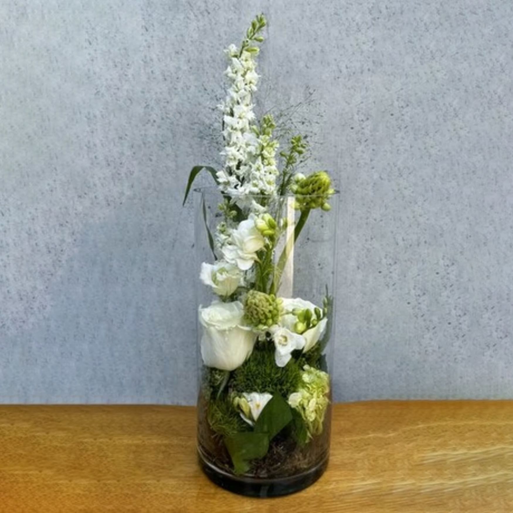 White floral arrangement in a tall clear glass vase
