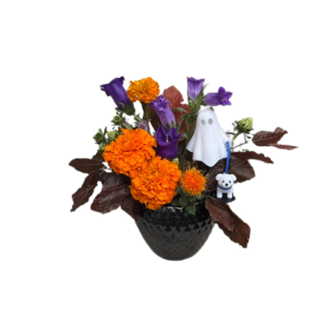 Orange and purple floral arrangement in a dark vase with Halloween figurines