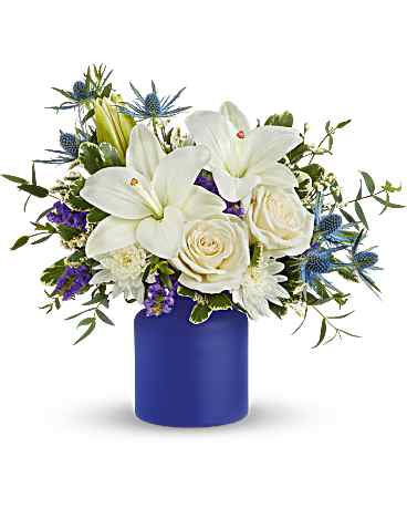 White lilies and roses in a blue vase with purple accents